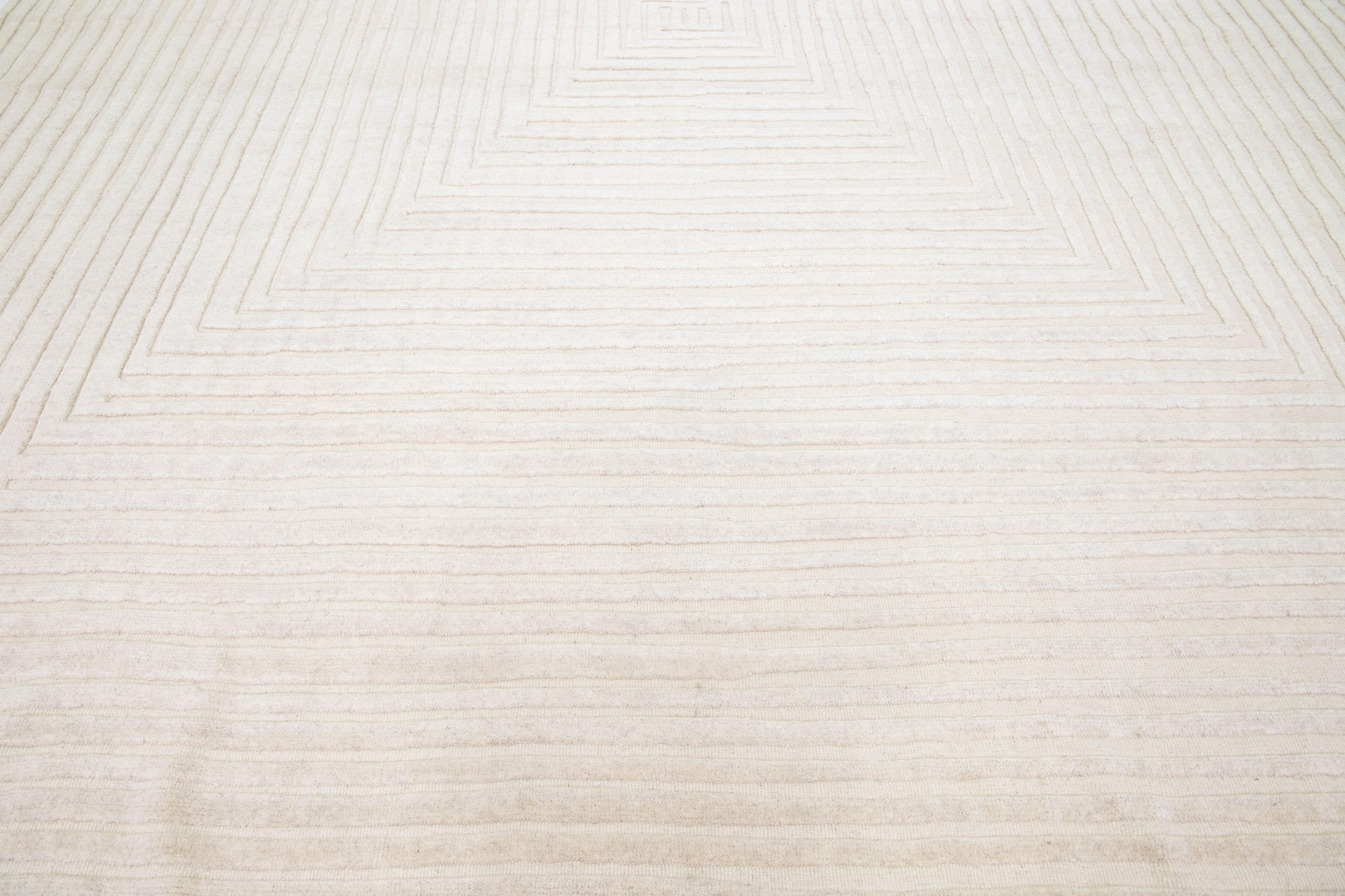 Bellissimo tappeto moderno in lana annodato a mano in stile marocchino con un campo di colore beige. Questo tappeto fa parte della Collezione Safi di Apadana e presenta un disegno a quadri Op Art senza cuciture in grigio.

Questo tappeto misura: