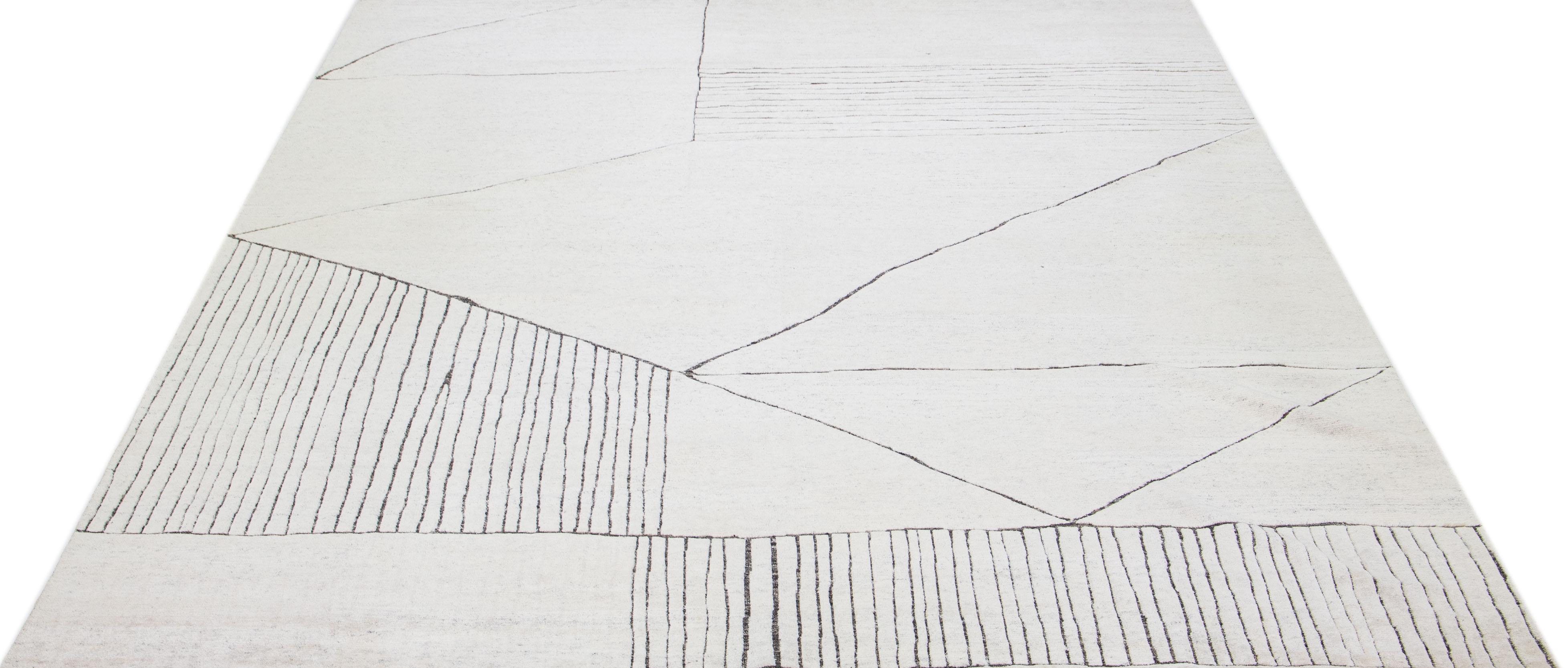 Beautiful modern Moroccan-style hand-knotted wool rug with an ivory color field. This rug is part of our Apadana's Safi collection and features a minimalist design in gray.

This rug measures: 12' x 15'.

Our rugs are professional cleaning