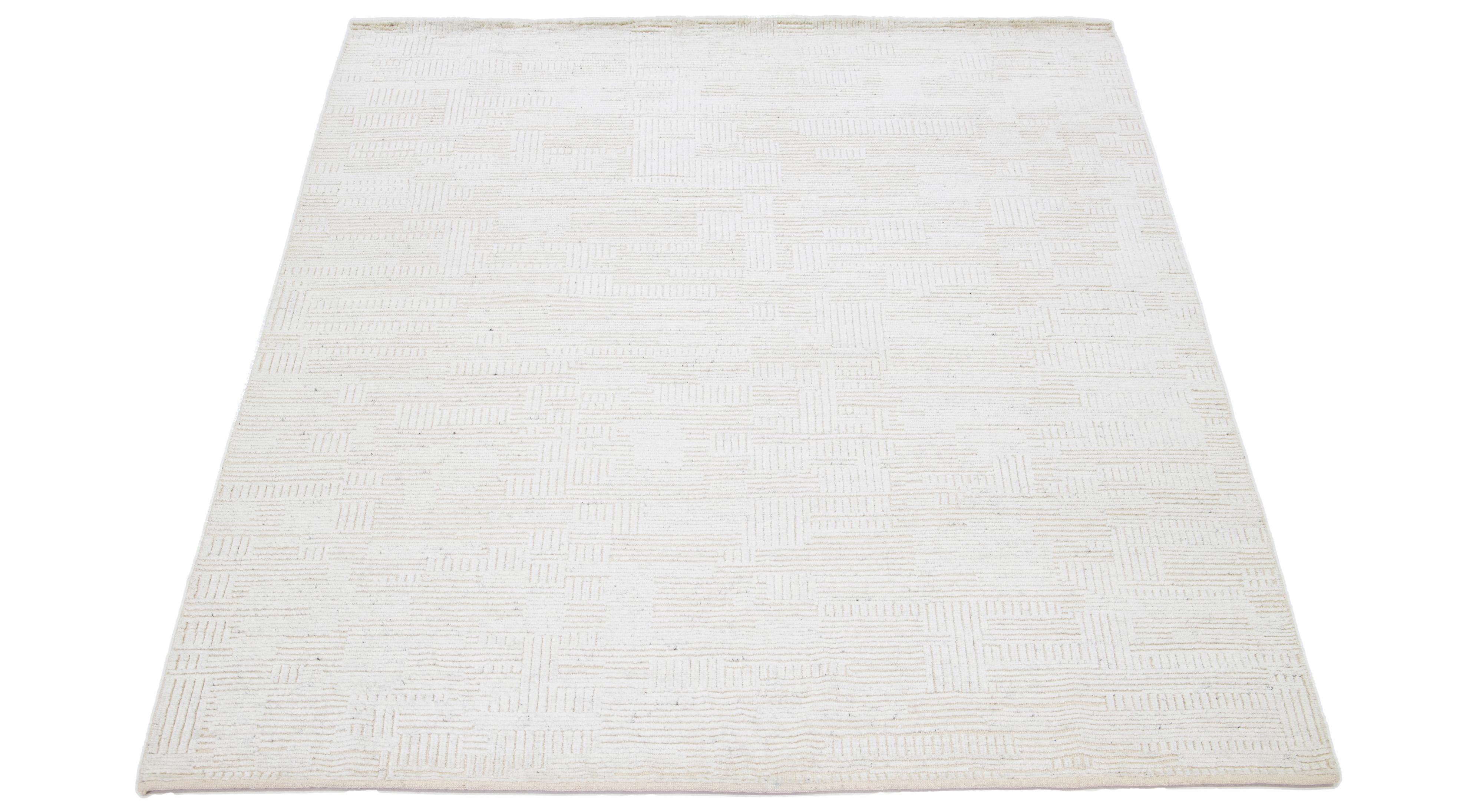 This hand-knotted wool rug showcases a modern Moroccan-inspired motif highlighting understated natural ivory hues against a bold beige foundation, creating a captivating geometric seamless pattern.

This rug measures 8' x 10'.

