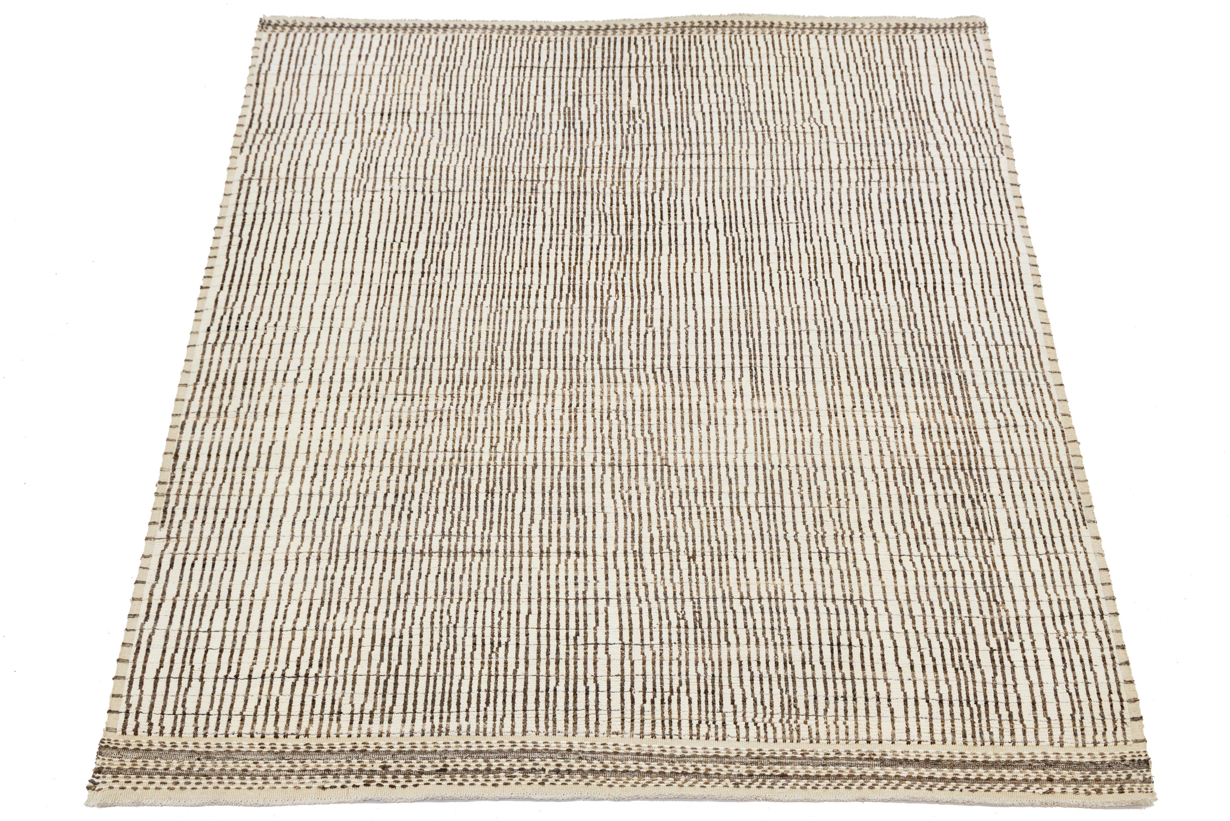 Artisan-crafted modern Moroccan wool rug featuring irregular vertical stripes in black on a warm ivory ground. The minimalist design is enriched by subtle texture and a detailed border, offering timeless appeal for contemporary, bohemian, or