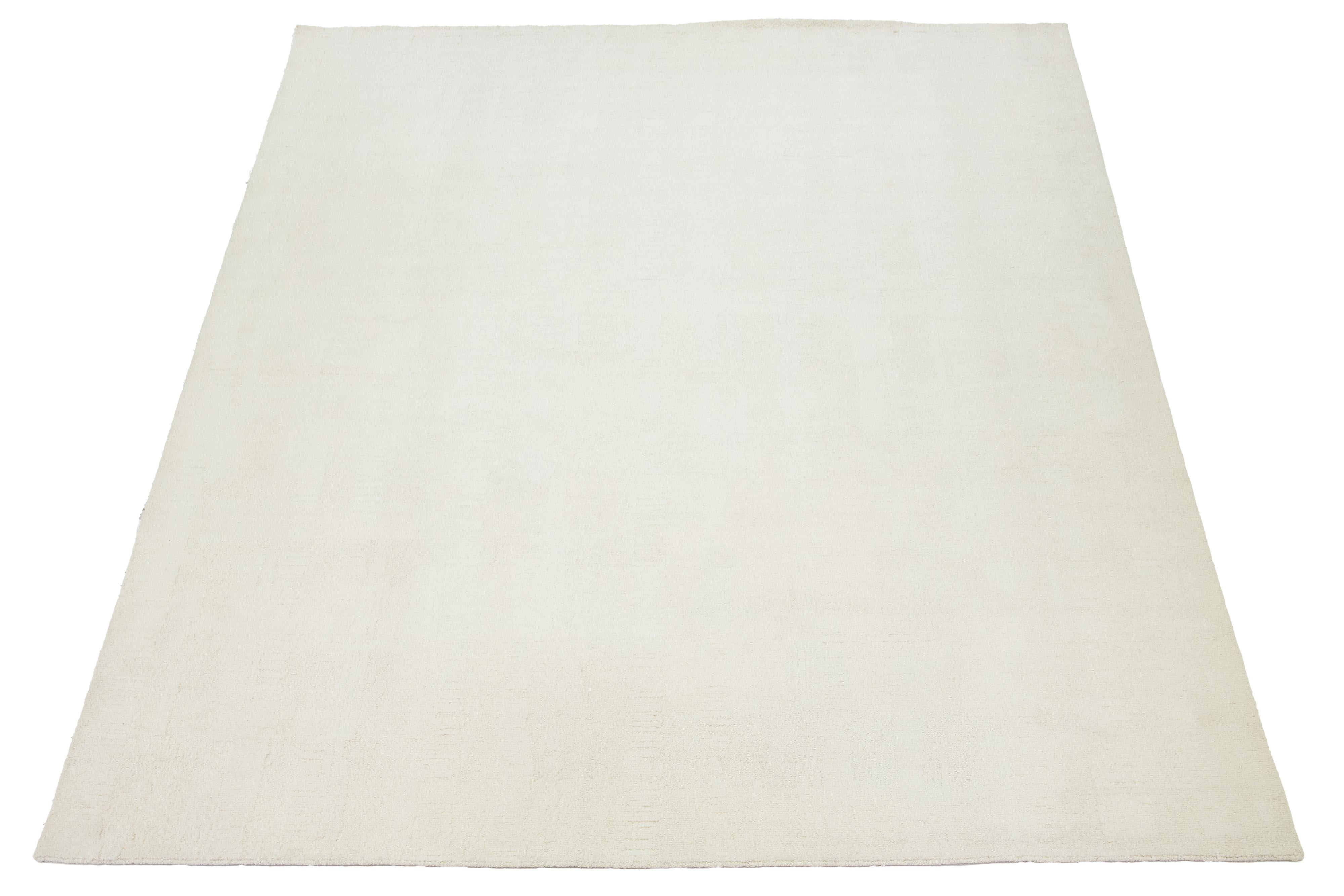 This hand-knotted Moroccan-style wool rug features a captivating minimalist aesthetic and a naturally hued ivory background.

This rug measures 11'11