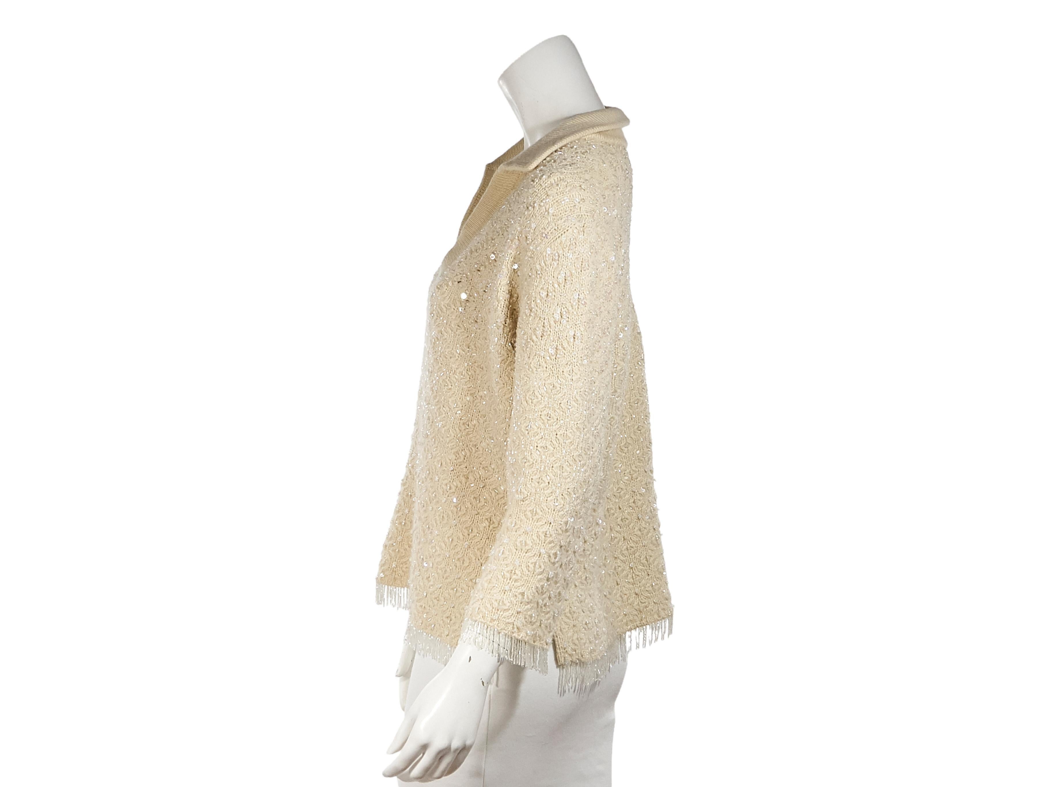 Product details:  Ivory sequined sweater by Oscar de la Renta.  Spread collar.  V-neck.  Long sleeves.  Beaded fringe cuffs and hem.  Pullover style.  36