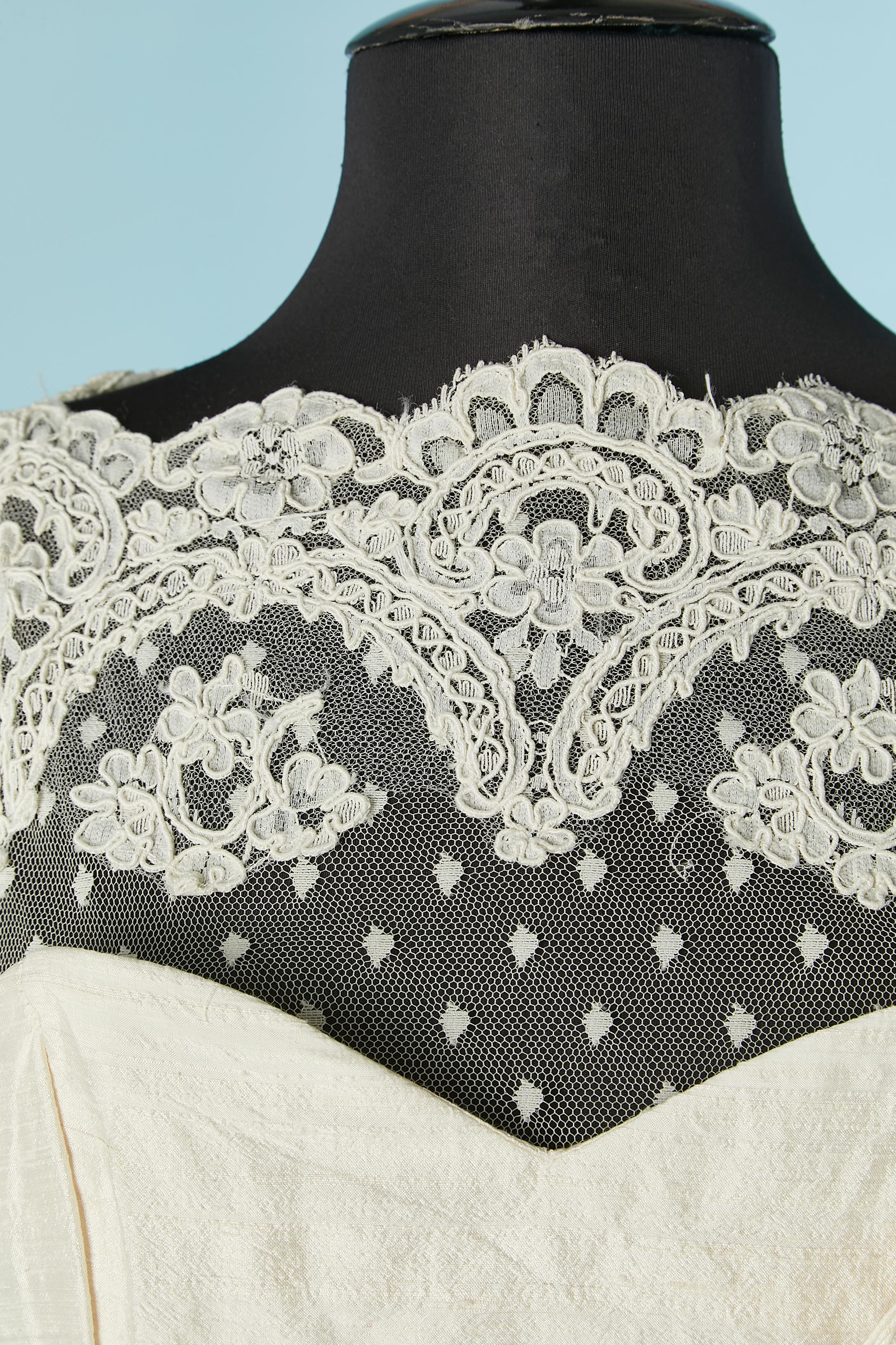Vestido de cóctel marfil de seda cruda y encaje con flor de tela.  No hay etiqueta de composición del tejido, pero el forro es probablemente de rayón. 
Cierre con cremallera en la parte central de la espalda + corchete. Cierre de corchete en la