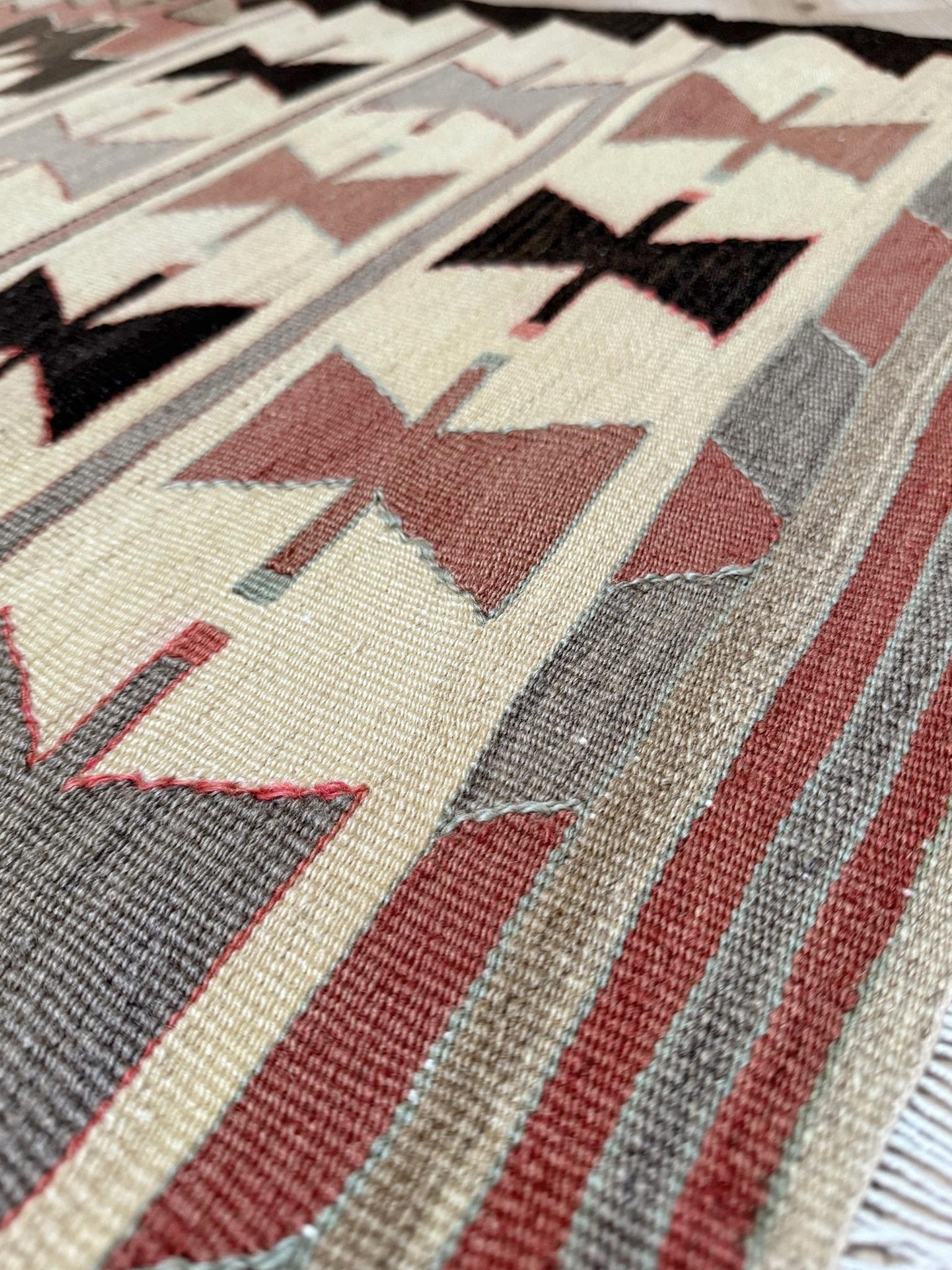 Dieser in der Region Mut in der Südtürkei handgewebte Kelim aus der Mitte des Jahrhunderts zeigt eine auffällige Anordnung von Schleifenmotiven und ein zentrales Stufenmedaillon - eine Anordnung, die optisch an die Navajo-Geometrie erinnert, aber