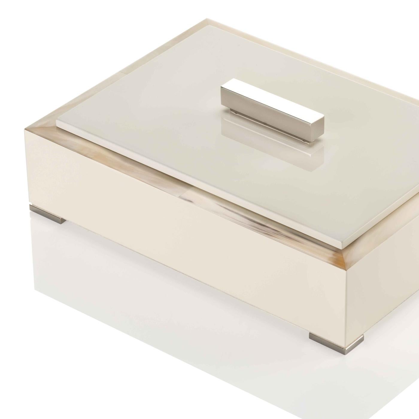 Enriched by a prized interior in ivory Tosca leather, this rectangular storage box crafted of exquisite Horn and wood showcases a structure in delicate ivory with a lacquered, glossy finish in the same hue. Four supporting feet in chromed brass