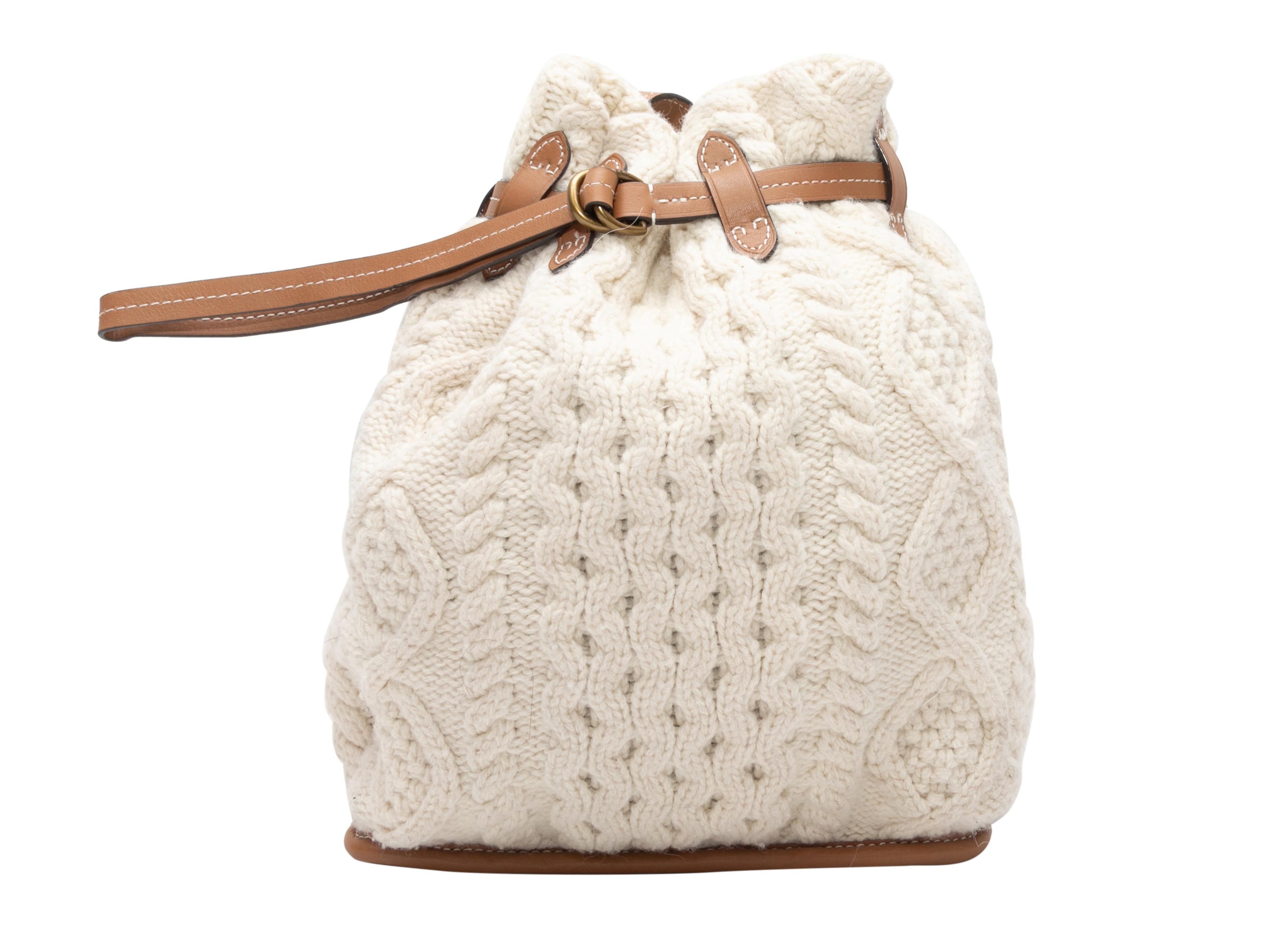 Ivory & Tan Polo Ralph Lauren Cable Knit Bucket Bag. This bag features a cable knit body, leather trim, gold-tone hardware, a single flat shoulder strap, and a top buckle closure. 12.5