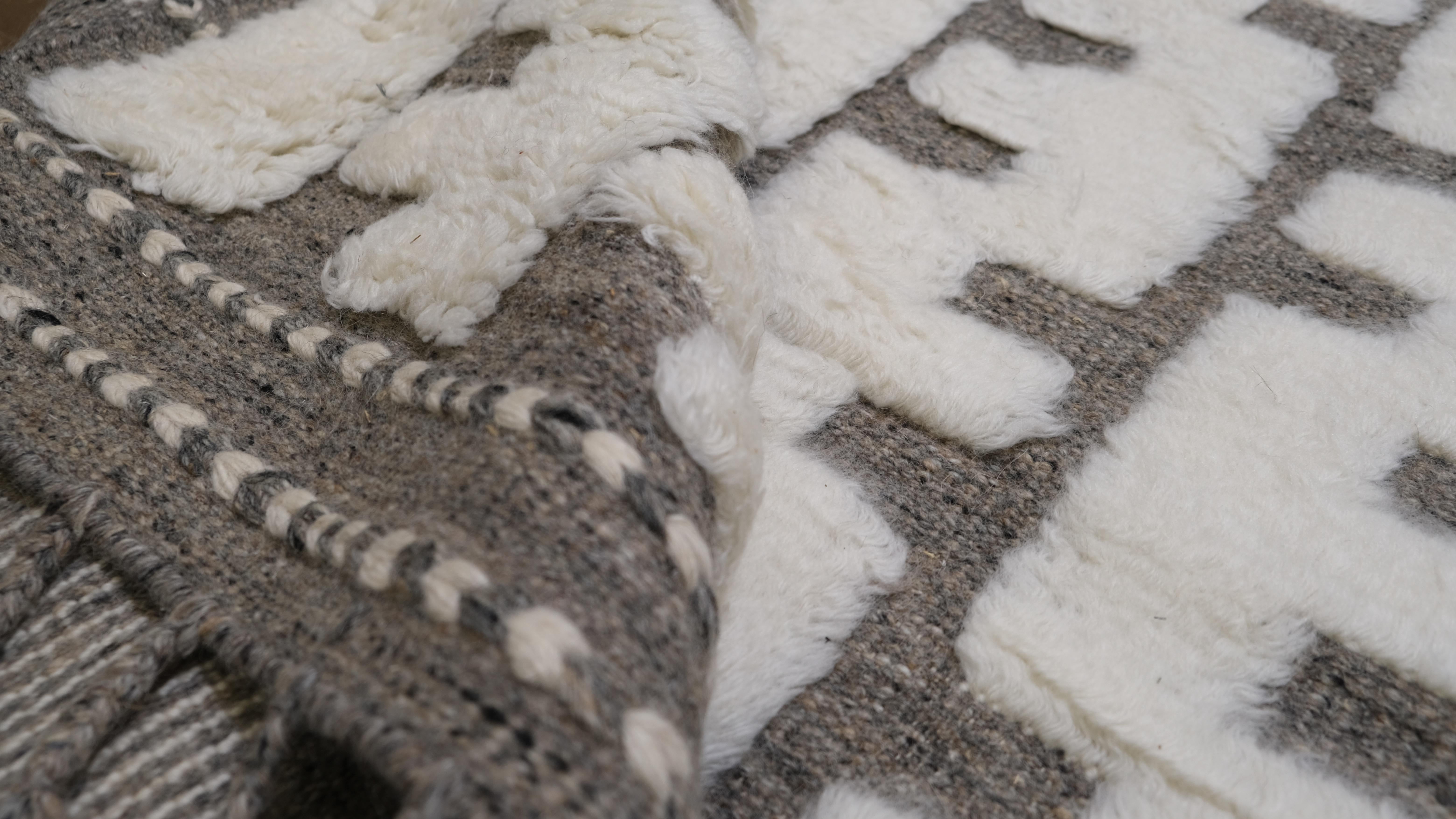 Make a statement with this exquisite hand-knotted wool rug, featuring a striking taupe and Ivory geometric pattern. The intricate, repeating design creates a rhythmic visual effect, blending traditional craftsmanship with a modern, minimalist