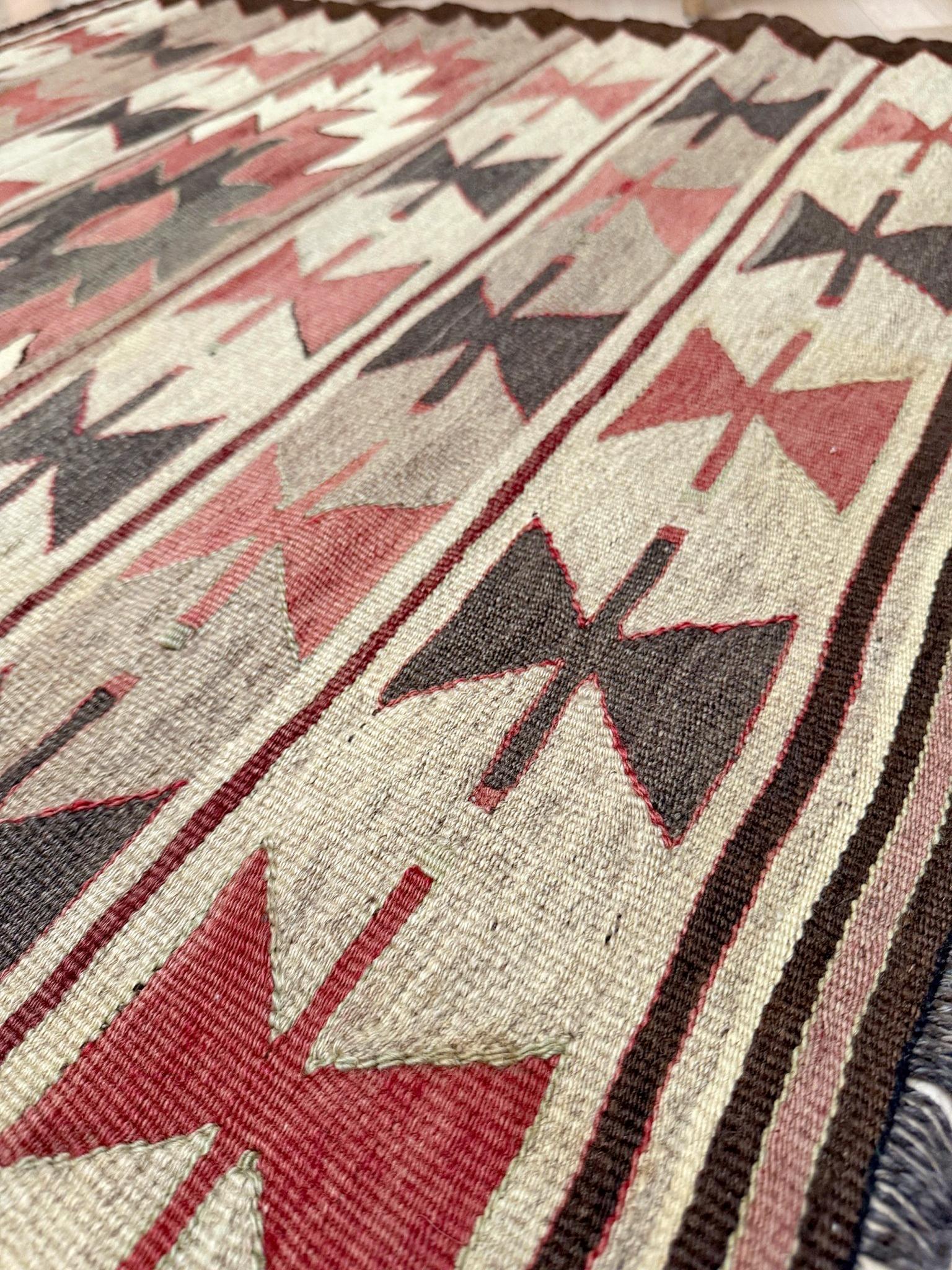 Tessuto a mano nella regione di Mut, nel sud della Turchia, questo kilim compatto della metà del secolo scorso presenta un motivo a papillon ripetuto disposto in bande orizzontali, punteggiato da un medaglione centrale a gradini - un motivo