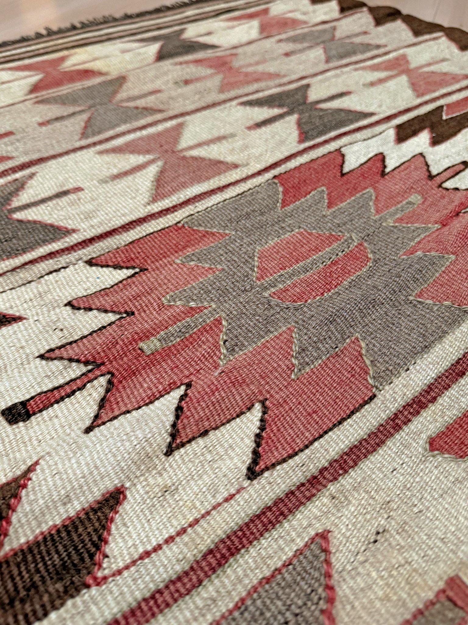 Tissé à la main dans la région de Mut, dans le sud de la Turquie, ce kilim compact du milieu du siècle présente un motif répétitif de nœud papillon disposé en bandes horizontales, ponctué par un médaillon central en escalier - un motif profondément