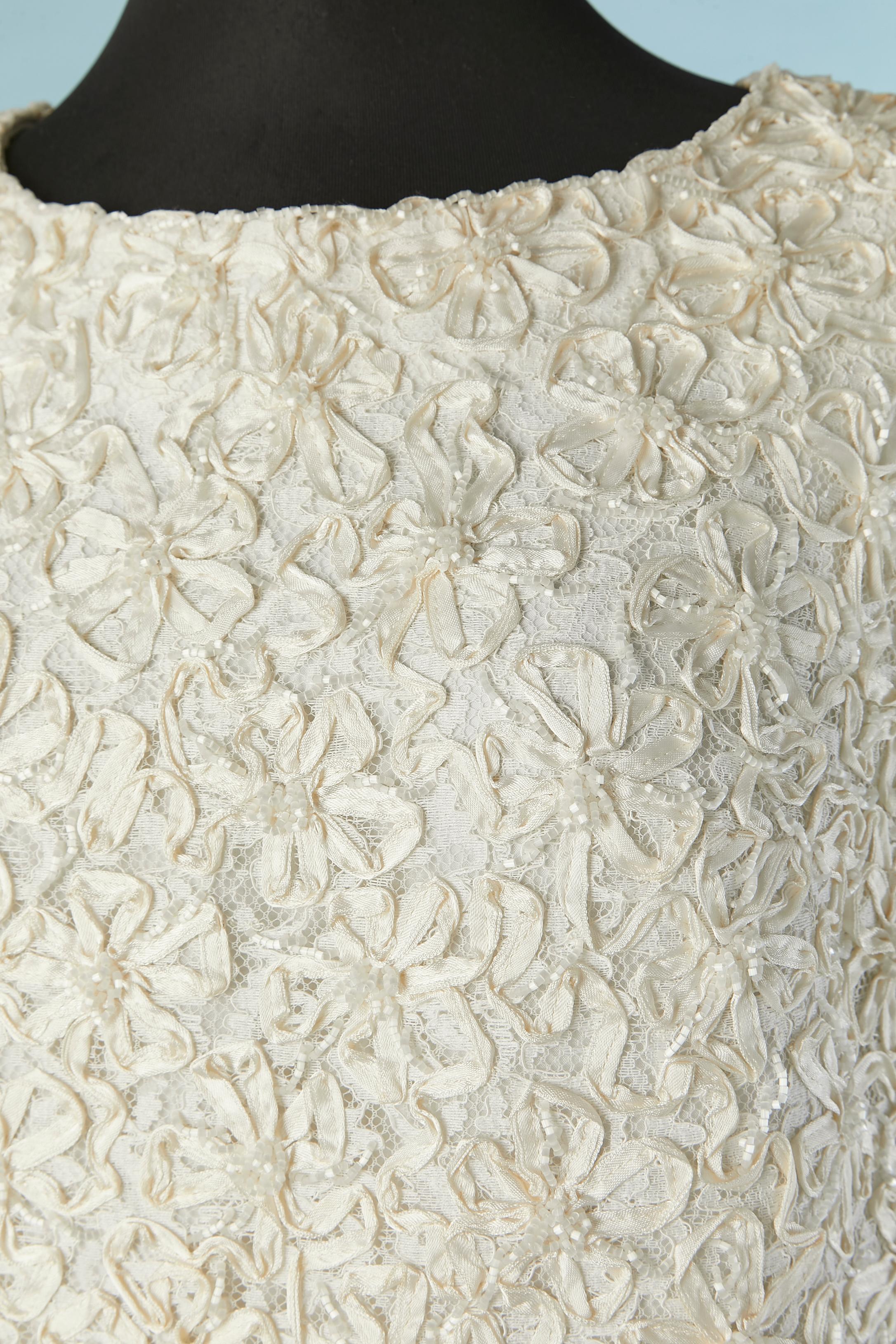 Ensemble de mariage ivoire composé d'un haut et d'une jupe en broderie de rubans et de perles sur une base de dentelle. Pas de composition de tissu mais la doublure est probablement en acétate ou en rayonne. 
Fermeture à glissière au milieu du dos