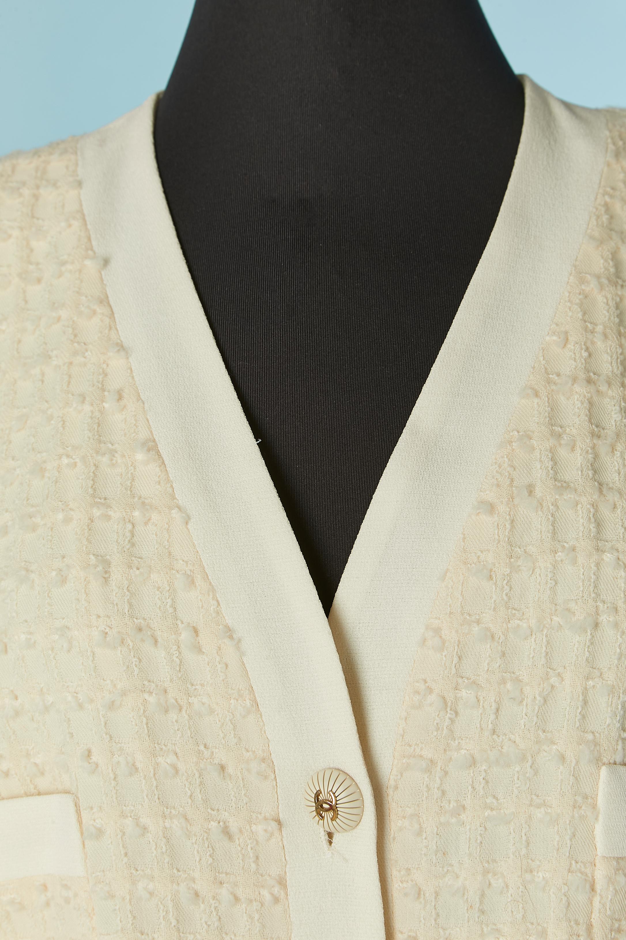 Einreihige Jacke aus elfenbeinfarbenem Tweed. Futter mit Markenzeichen aus Seide. Schulterpolster. Markenknopfverschluss in der vorderen Mitte und an den Manschetten. Taschen. Kette auf der Innenseite der Jacke am unteren Rand.
GRÖSSE 42/44 (Fr) L 
