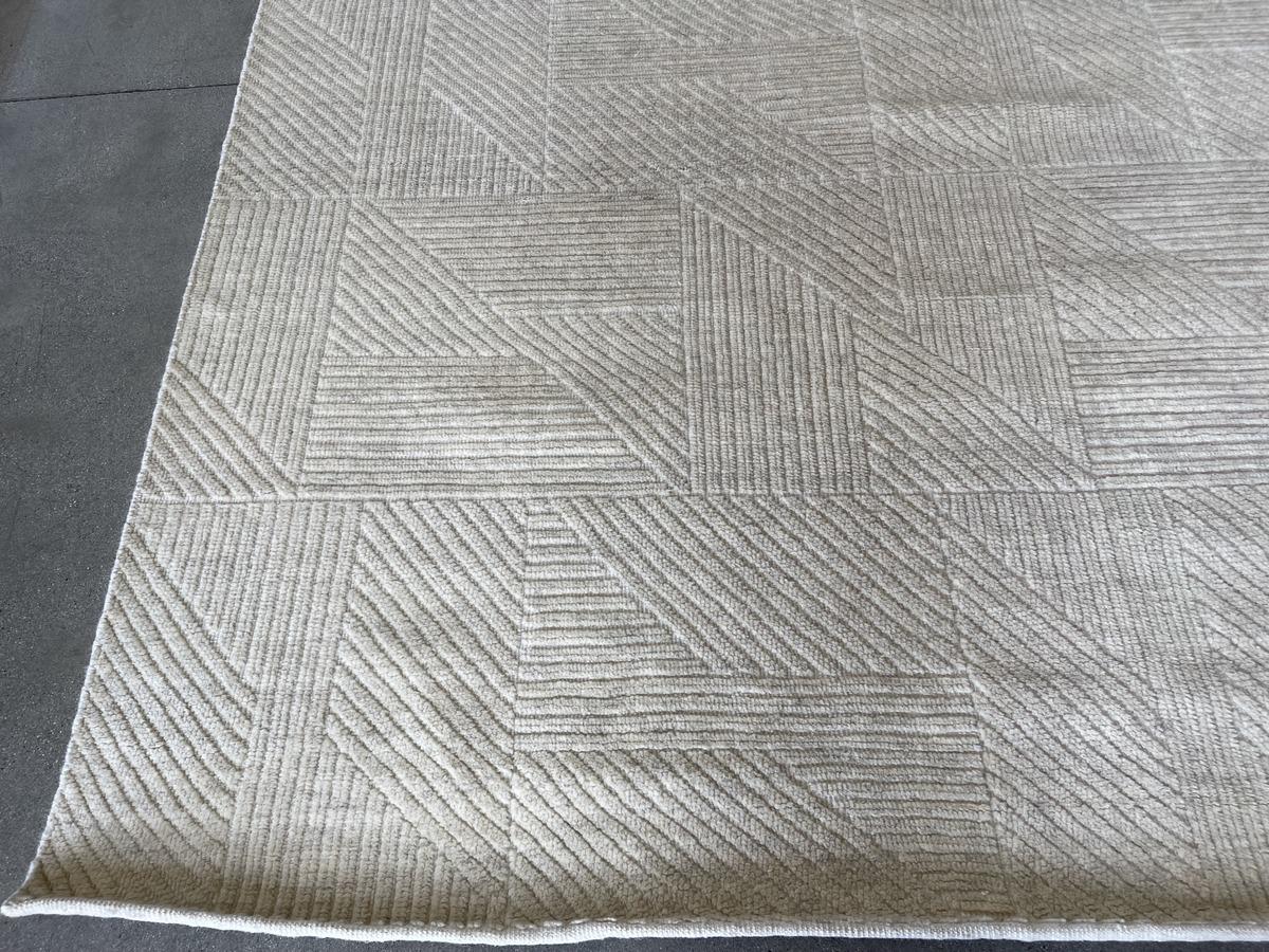 Dieser prächtige elfenbeinfarbene Teppich wird in Indien von Hand gefertigt und weist ein subtiles geometrisches Muster auf, das durch Reihen von dicken, niedrigflorigen Fasern erzeugt wird. Wunderschön anzusehen und wunderbar weich unter den Füßen.