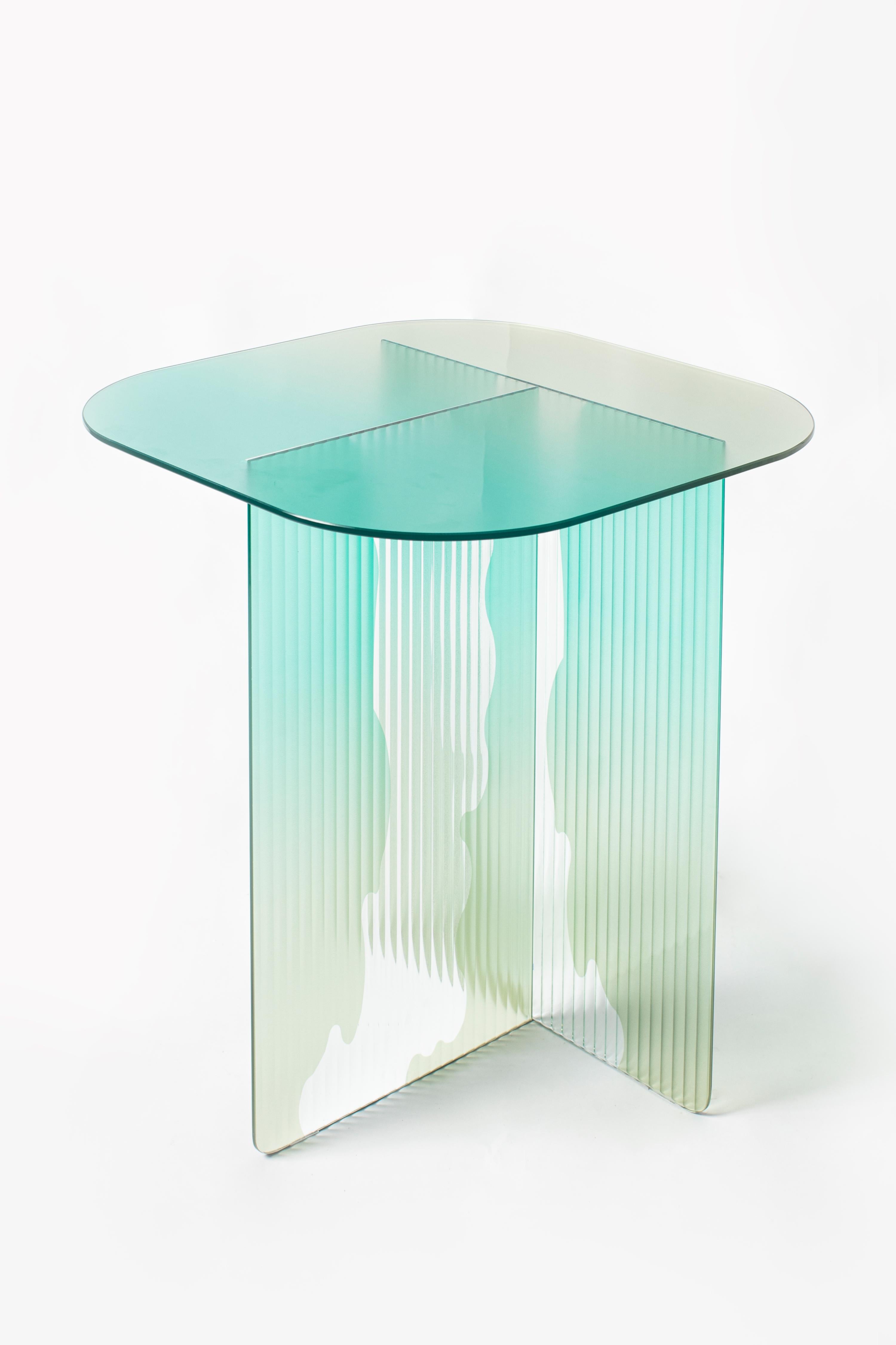 Ivy II Side Table by Yugen Lab
Dimensions: D 50 x W 50 x H 54 cm.
Materials: 6mm tempered ribbed glass and flat tempered glass.

Ivy-II is a vibrant glass side table with a coastal color palette, exuding tranquility. Its tree bark-patterned legs and