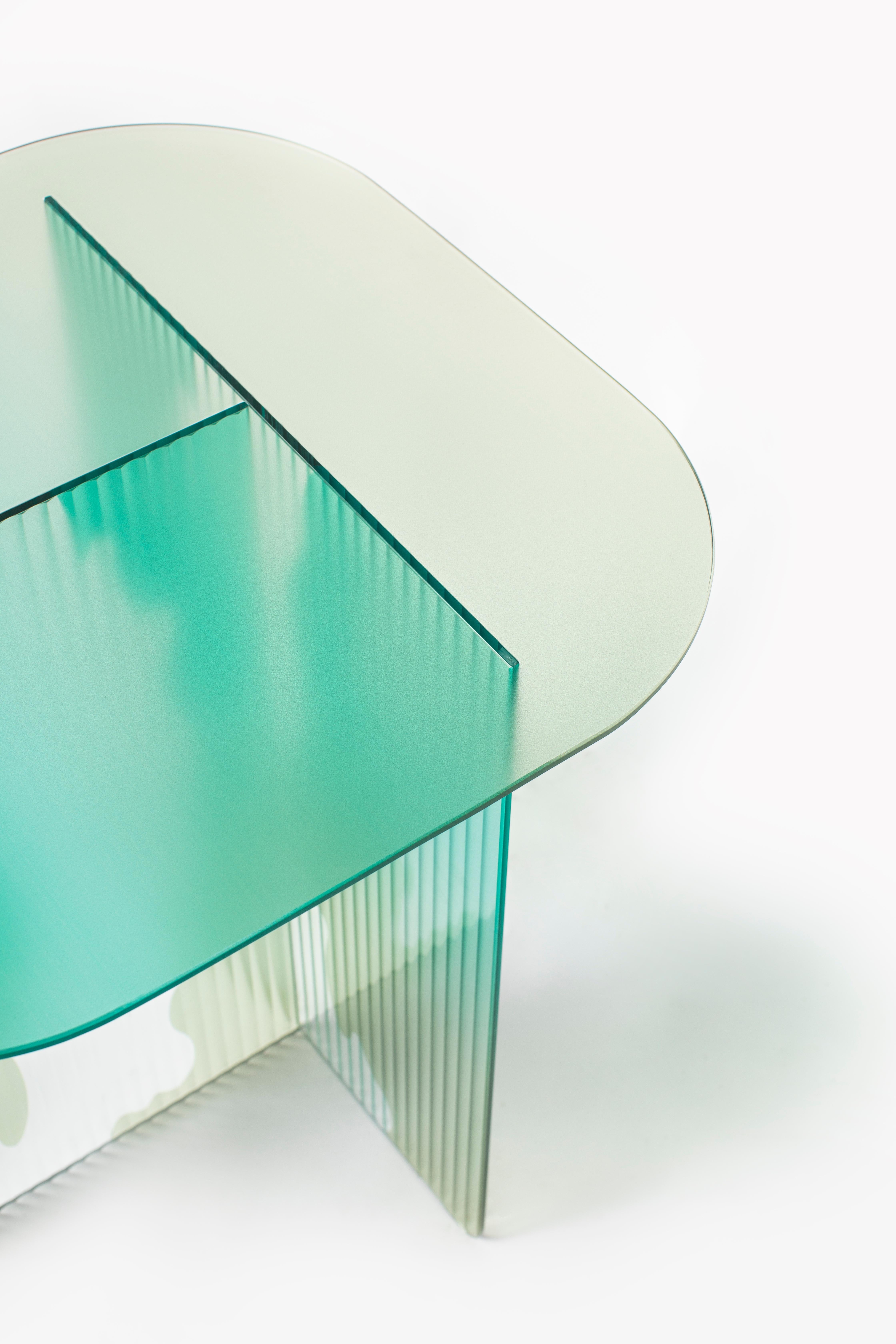 IVY-II is the twin sibling of IVY-I, designed as a side table inspired by colors found in nature. The tabletop is crafted from flat glass and colored using a printing technique. The legs feature ribbed glass with the same color tones, adorned with a