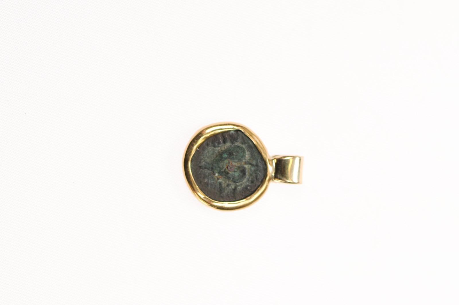 A dainty Ivy leaf coin pendant from Ancient Greece trimmed in 22 karat gold. This bronze coin from the 2nd century BC has a marvelous verdigris patina to demonstrate its age. This sweet ivy leaf looks just like a heart on the front, and has the worn