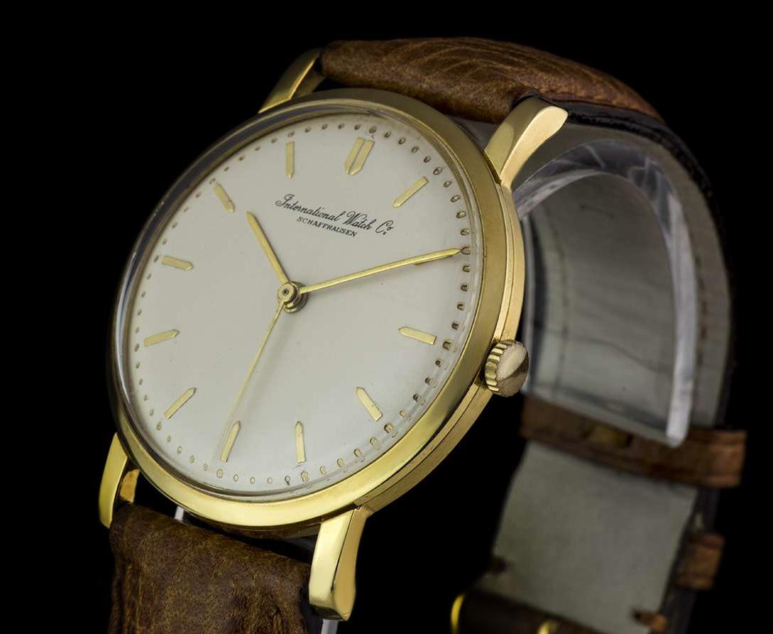A 33 mm 18k Yellow Gold Vintage Men's Wristwatch, cream dial with applied hour markers, a fixed 18k yellow gold polished bezel, a brown leather strap with a gold plated pin buckle (both not by IWC), plastic glass, manual wind movement, in excellent