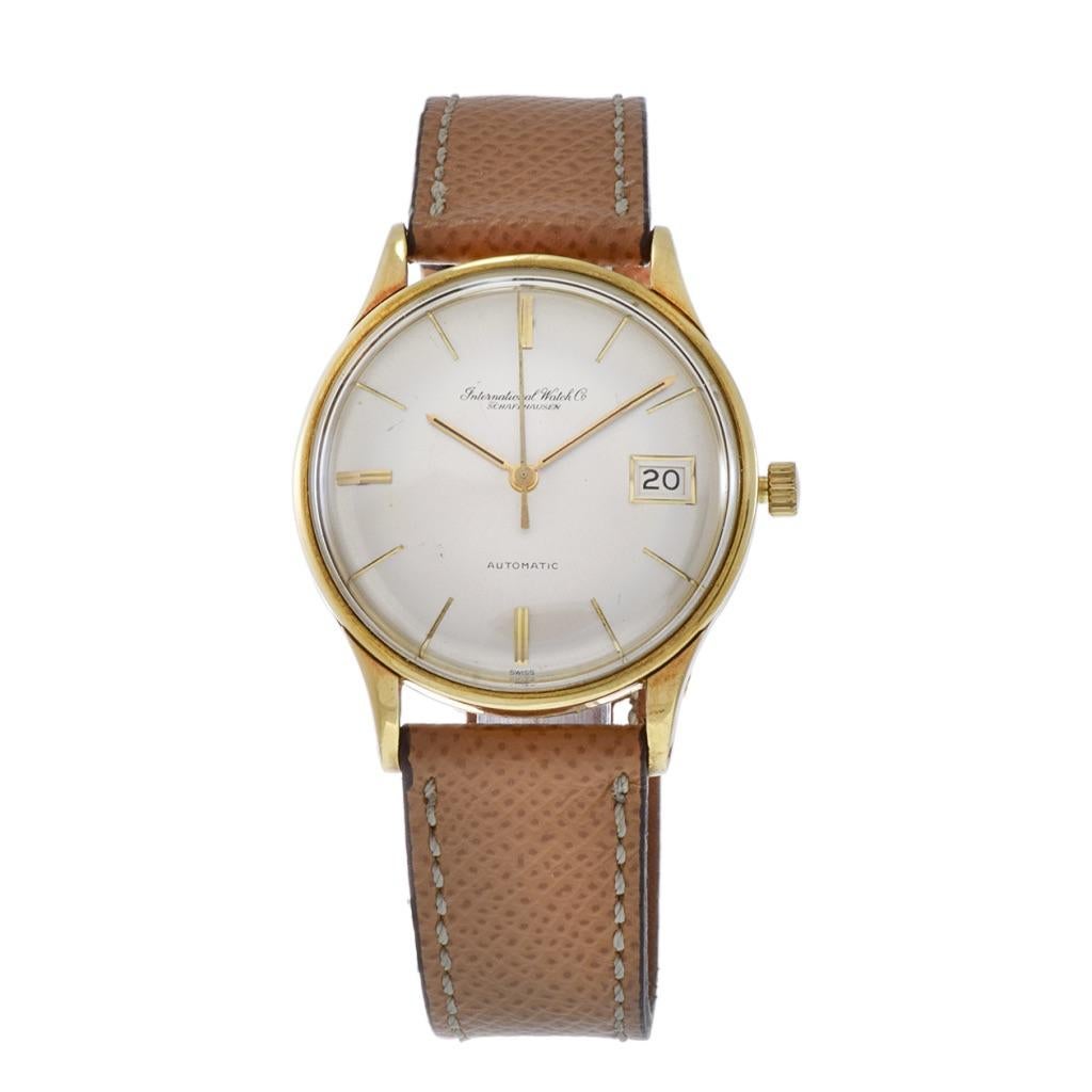 Introducing the IWC (International Watch Co.) vintage 1960's wristwatch, a timeless embodiment of elegance. This exquisite timepiece features a 34mm round 18kt yellow gold case with a classic pearlized dial with date, adorned with gold stick markers
