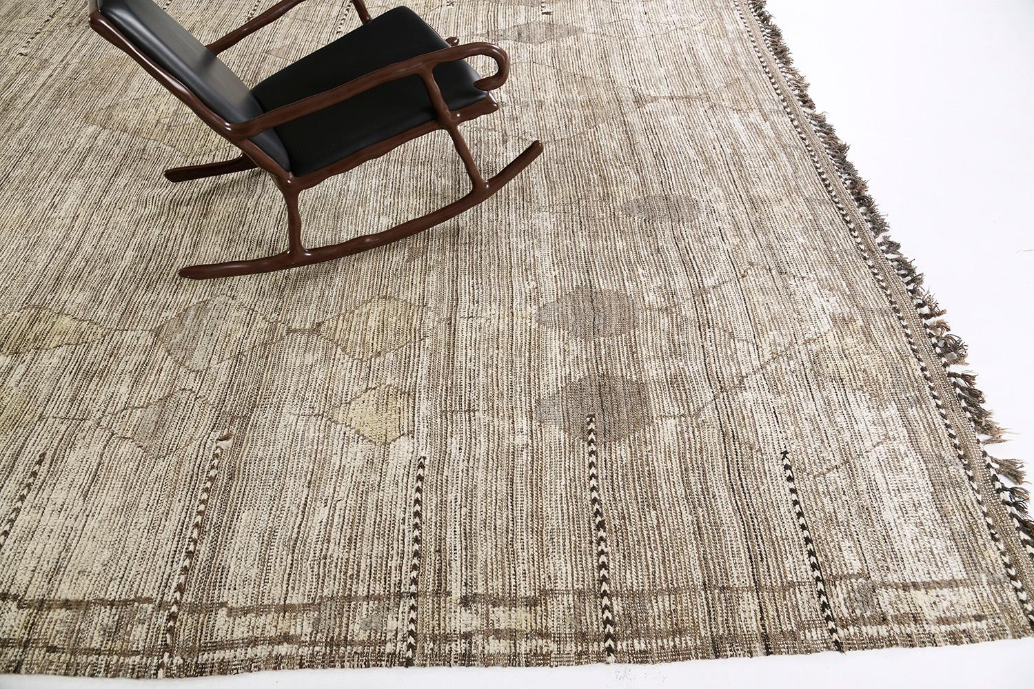 Izil is a natural wool pile weave and modern-day interpretation of the Moroccan world. The rug is composed of irregular diamond shapes that are latticed sporadically and resemble the organic fibers of nature covered by linear strokes of gray, brown,