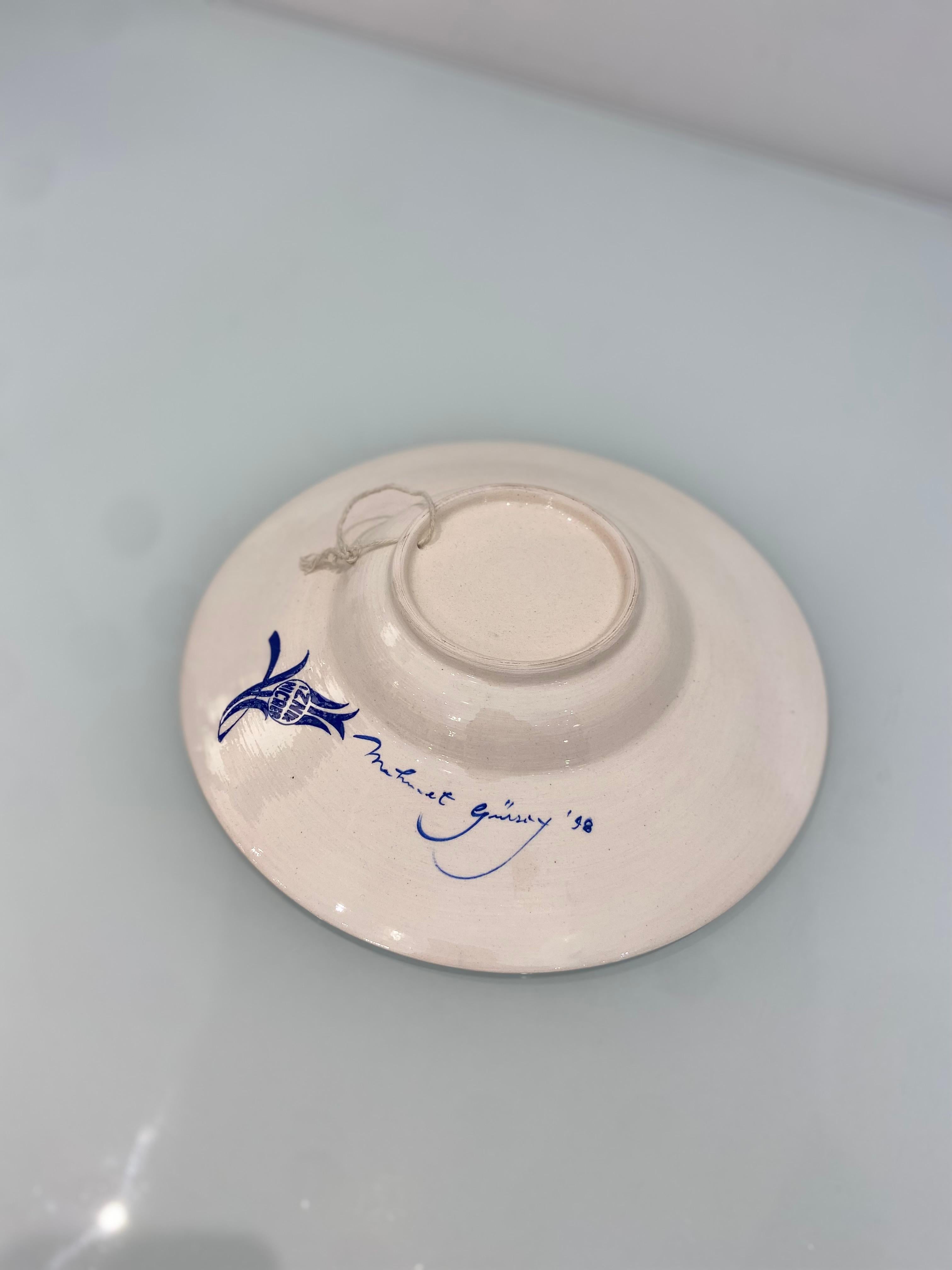 Un plato decorativo vintage único realizado por un artesano turco en Iznik, Turquía. 

El antiguo nombre de la ciudad es Nicea, y es una zona conocida por sus azulejos y cerámicas pintados a mano de la época otomana. 

Este hermoso plato presenta