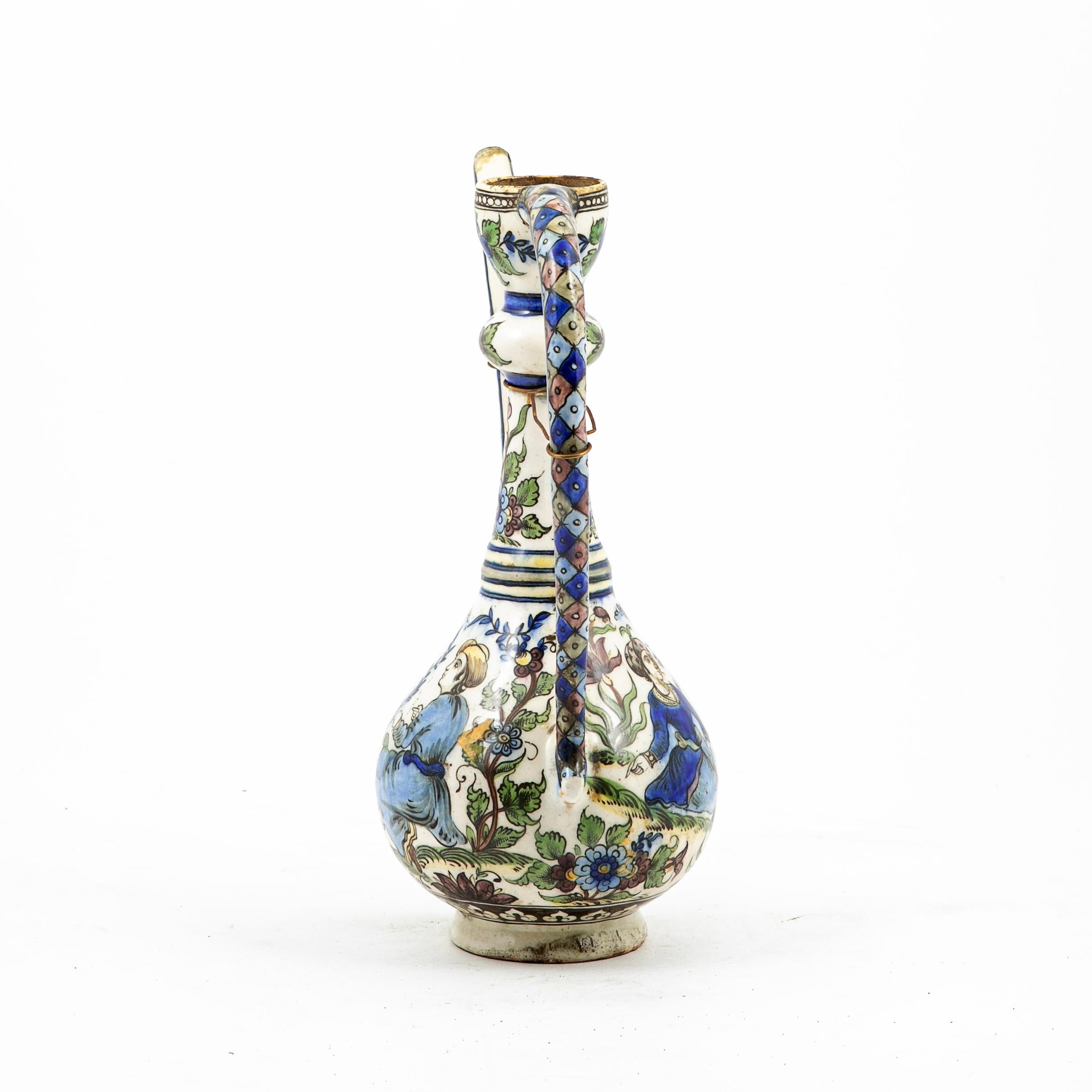 19th Century ottoman iznik pottery jug or pitcher with long handle and spout.
Ceramic hand painted with colorful middle eastern scenery, flowers and foliage. Restored.

The first examples of Iznik pottery date back the 15th century and there is a