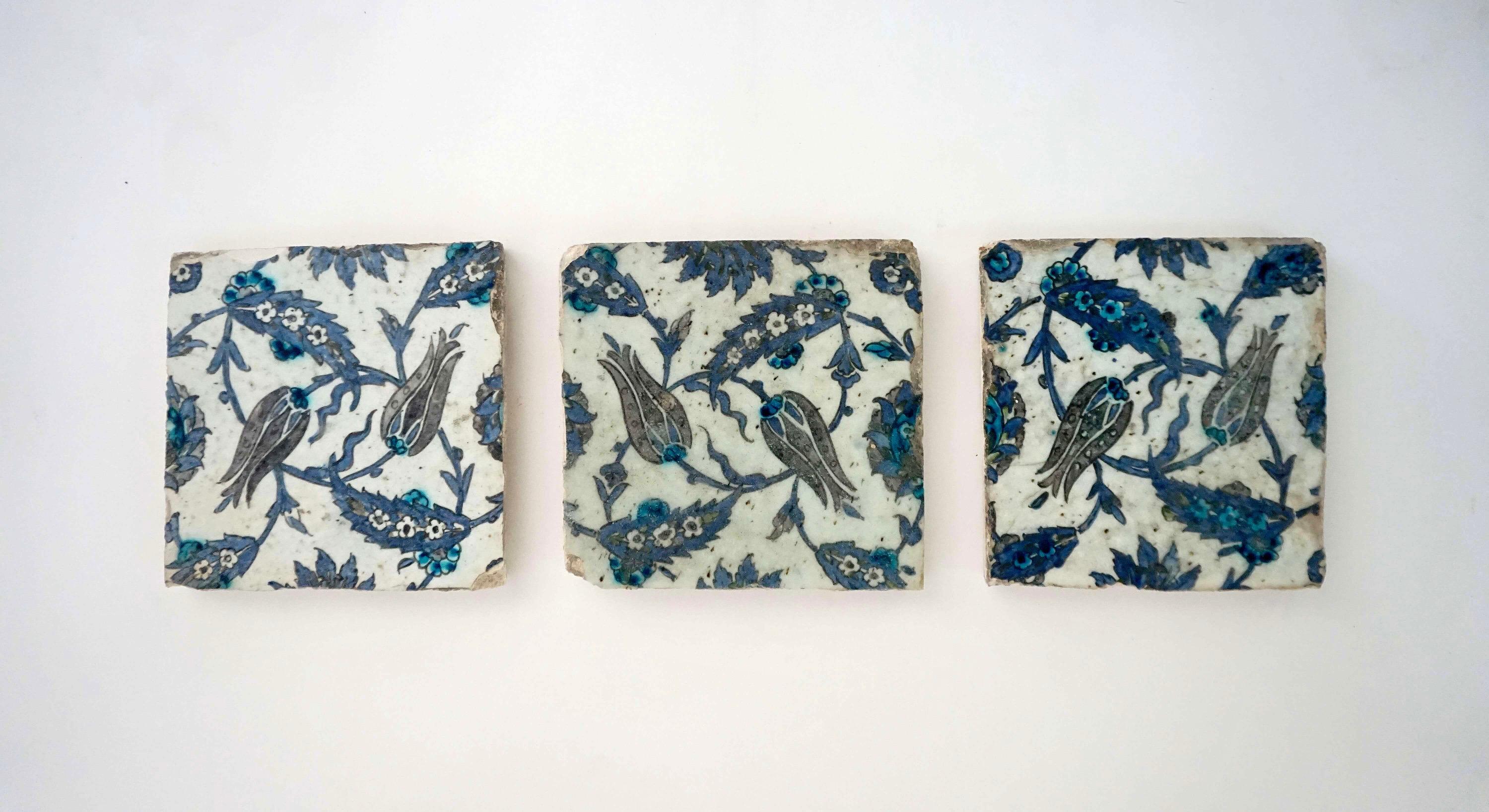 A collection of three 17th century Turkish Ottoman Iznik pottery wall tiles having underglaze-polychrome decoration of stylized tulips and 'saz leaf' designs in black, blue, and turquoise on white background.