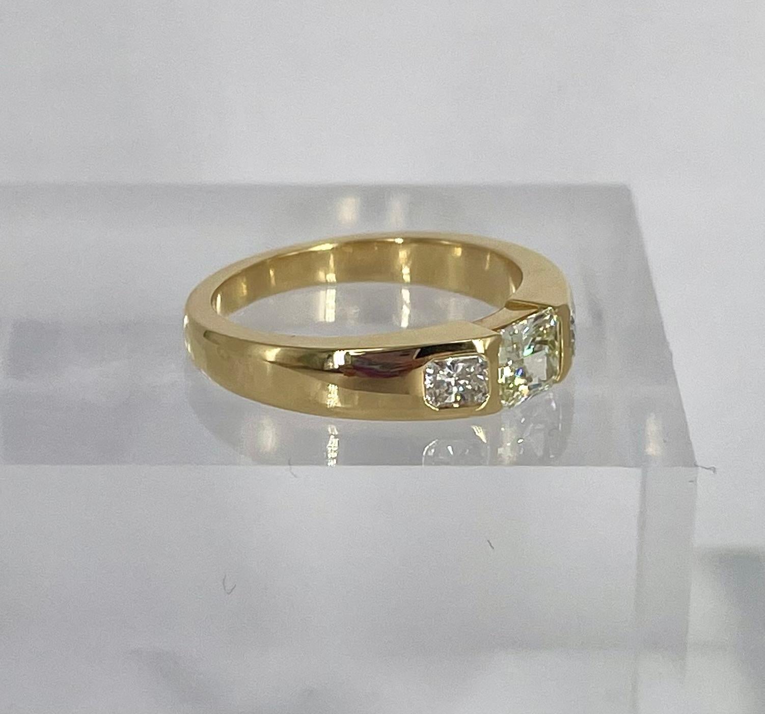 This sleek, bold band is the perfect addition to your stack or makes a statement on its own! This ring features a 0.55 carat fancy light yellow radiant set east-west, following the line of the band. On either side are two white radiant diamonds, F