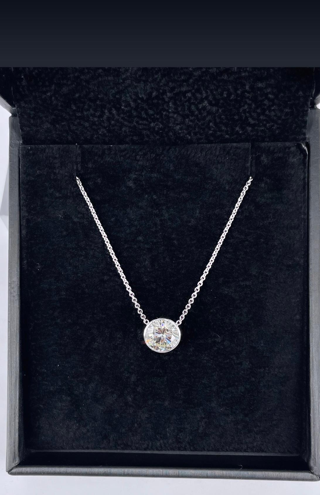 This simple and stunning diamond pendant is the perfect everyday necklace. Crafted in 18K white gold, the narrow bezel delicately frames and emphasizes the diamond. The 1.42 carat round diamond is GIA certified M color and VS2 clarity. The diamond's