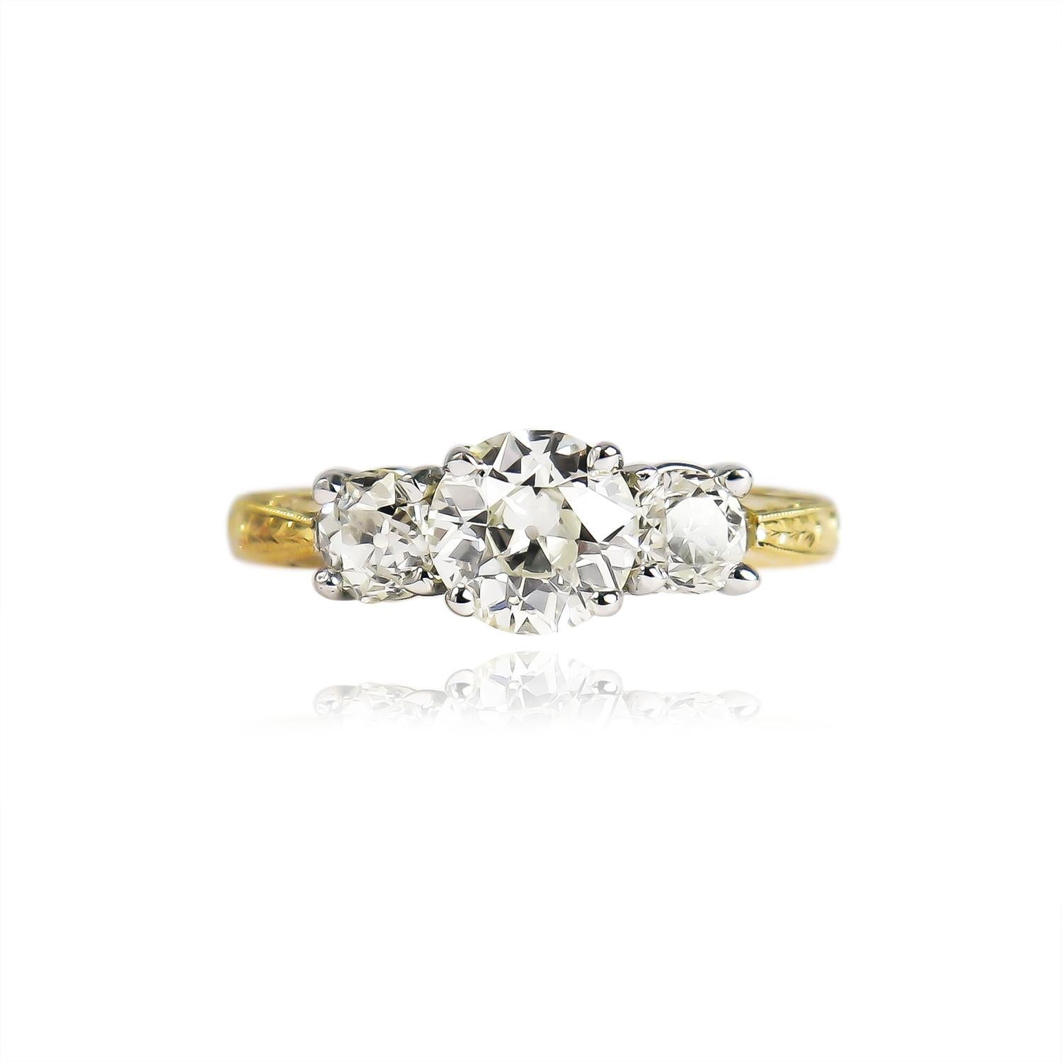 This charming, three-stone ring from the J. Birnbach vault features three Old European cut diamonds of L color and SI clarity = 1.44 carat total weight. Set in a 14K white and yellow gold mounting with engraved details throughout the shank, this