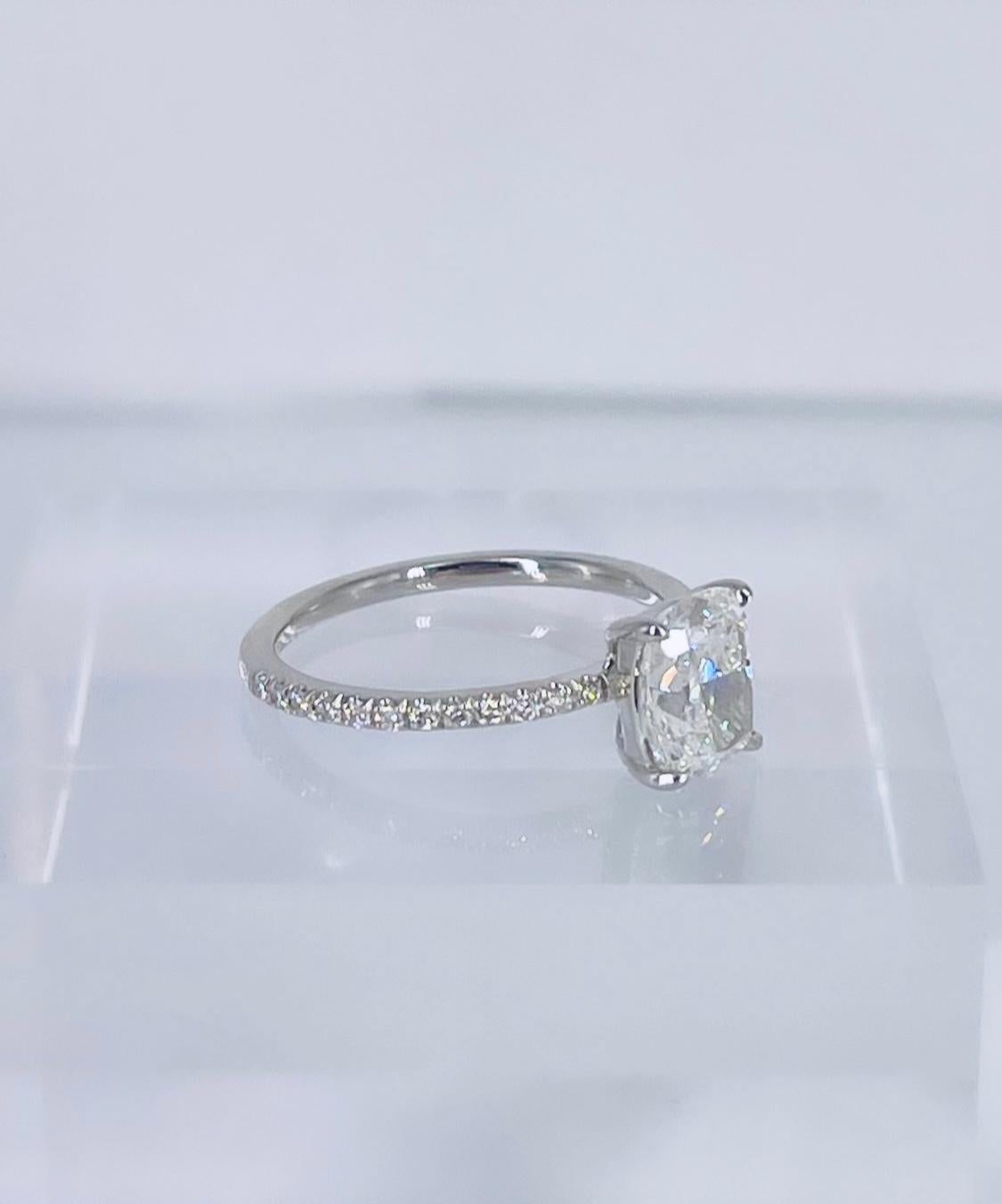 Sparkling and delicate, this cushion pave solitaire engagement ring is a modern classic! This ring features a 1.51 carat elongated cushion certified by GIA to be H color and SI1 clarity. The diamond is white and has a lively brilliance. The