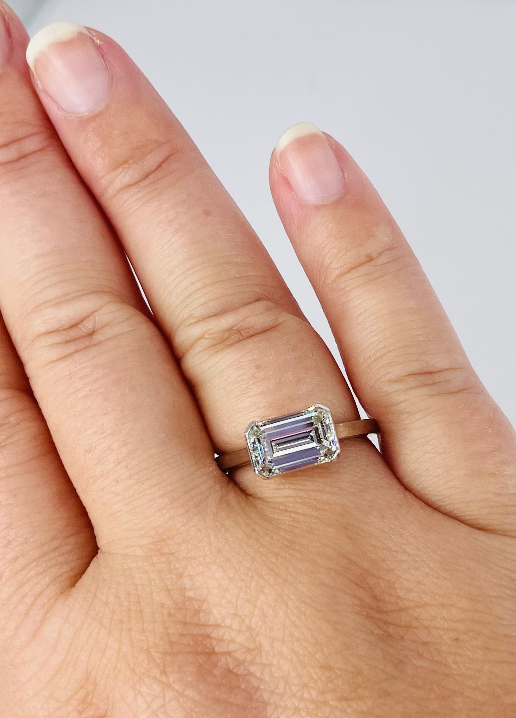 Sleek and sophisticated, this modern take on the classic solitaire is unique yet timeless. The 2.01 carat emerald cut diamond is certified by GIA as I color and VS1 clarity. The diamond is white and has a lively sparkle, and there are no visible