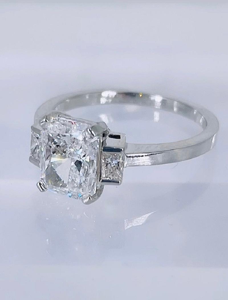 This sparkling engagement ring by J. Birnbach features a gorgeous GIA certified 2.01 carat radiant cut diamond. The diamond is D color and SI1 clarity. D is the highest color grade, and the diamond has no visible inclusions. Two princess cuts (total