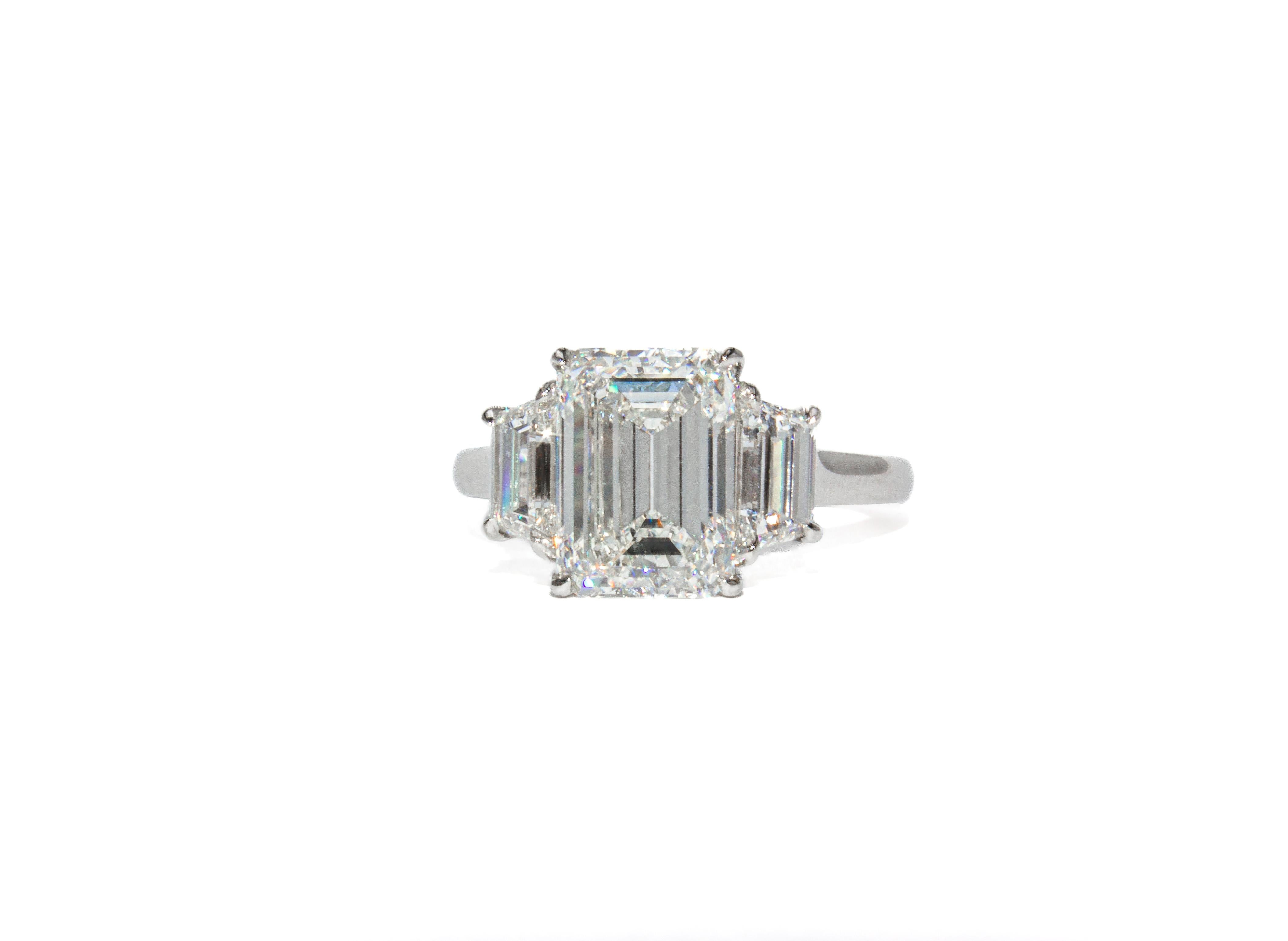 Dieser zeitlose Dreisteinring aus Platin besticht durch einen 3,08 Karat schweren Diamanten im Smaragdschliff mit der Farbe H und der Reinheit VS2, der vom GIA zertifiziert wurde. Der Mittelstein ist wunderschön proportioniert, mit einem sauberen