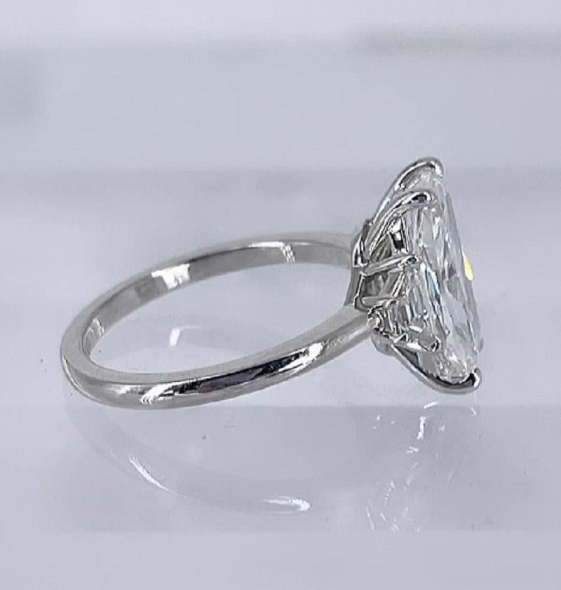 This sophisticated and unique three stone ring by J. Birnbach features an exceptionally long and narrow 2.50 carat cushion cut diamond. The diamond is certified by GIA as G color and SI1 clarity. Two brilliant cut trapezoids, total 0.27 carats,