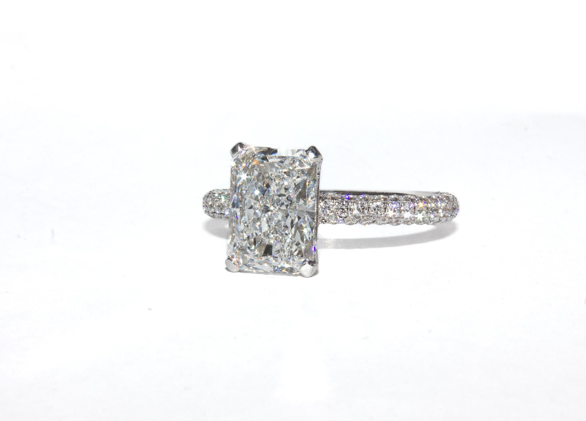 This striking 14K white gold ring is designed to dazzle from every angle. At the center is a vibrant 3.02 carat radiant cut diamond, certified by GIA as E color and SI2 clarity—offering exceptional brilliance and near-colorless quality. Surrounding