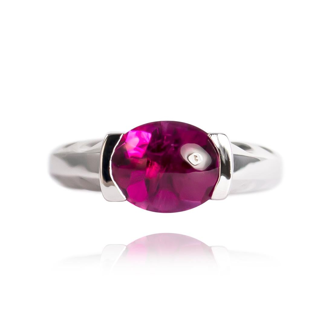 This bold and architectural ring is a one of a kind piece-every aspect of this ring is unique! It features a 3.35 carat cabochon oval rubellite of a saturated, intense, purplish-pink color. The open half bezel setting emphasizes the stone, and