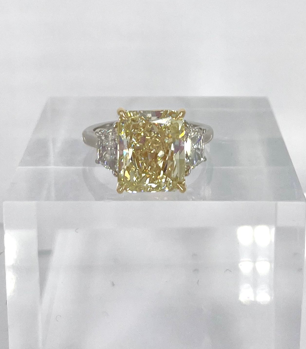 This fancy light yellow diamond three stone engagement ring is a showstopper! The yellow diamond gives new energy to the elegant and simple design. The center diamond is a 5.62 carat radiant, graded by GIA as Fancy Light Yellow and VS2 clarity. The