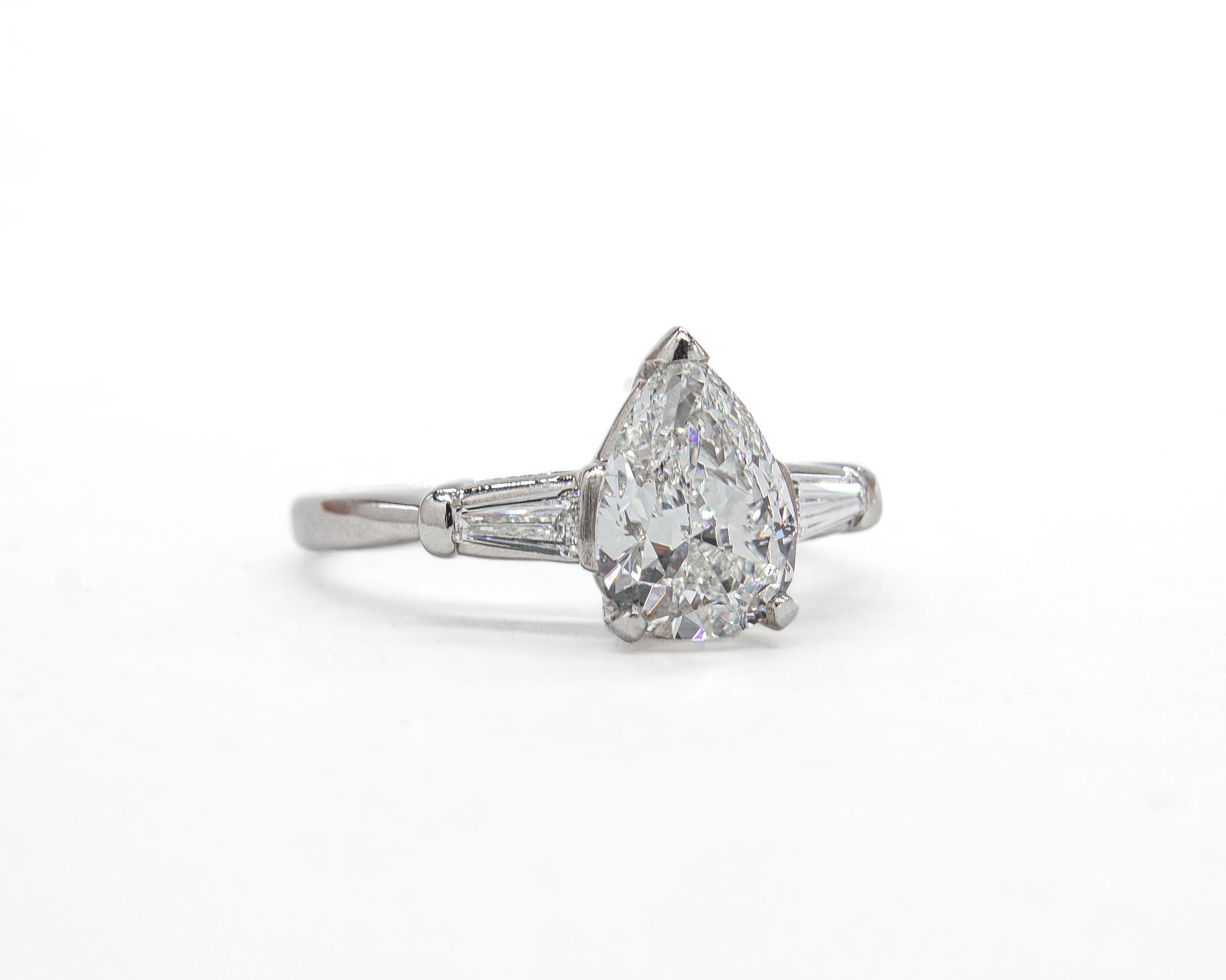 Questo raffinato anello in platino presenta un diamante a forma di pera da 1,38 carati, certificato dalla GIA con colore G e purezza SI2. La forma del diamante offre una silhouette aggraziata, con un'elegante conicità e sfaccettature brillanti che
