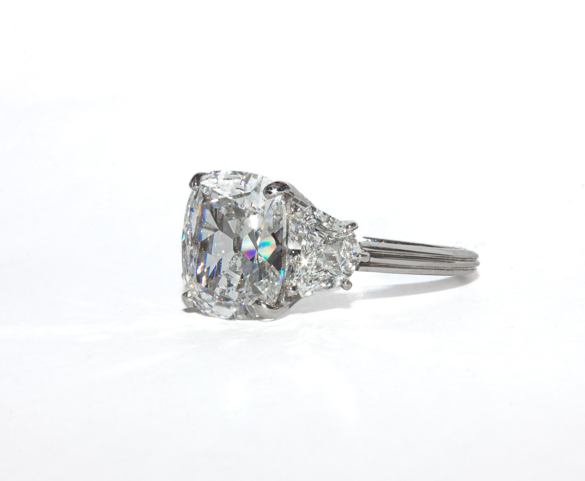 This stunning three-stone ring by J. Birnbach showcases a beautifully cut 4.34 carat cushion brilliant diamond at its center. Graded H color and SI1 clarity by GIA, the diamond exhibits exceptional brilliance, with a lively fire and a softly rounded