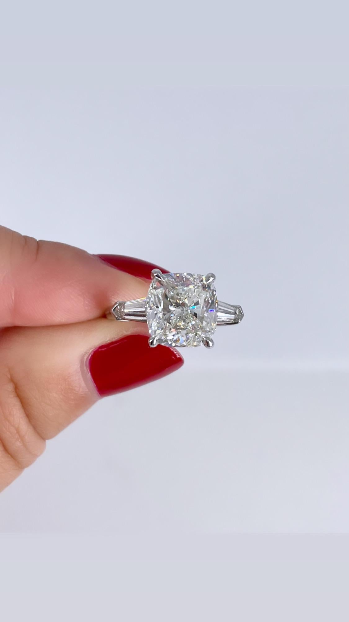 Dieser elegante Verlobungsring ist ein einzigartiges Beispiel für einen zeitlosen Stil. Es ist selten, dass man einen kissenförmigen Diamanten mit spitz zulaufenden Baguettes sieht, und wir lieben diese Kombination! Der Ring ist mit einem 4,64 Karat