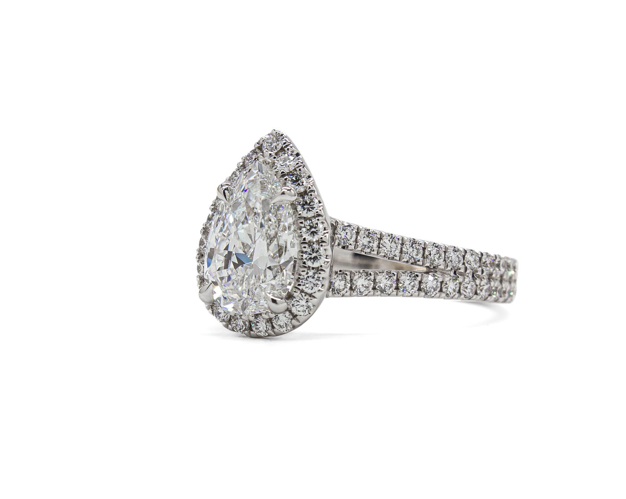 This elegant halo engagement ring is a modern classic with a striking presence. Crafted in 14K white gold, the ring features a 1.50 carat pear shape diamond, certified by GIA as E color with exceptional VVS2 clarity. The diamond’s bright white hue