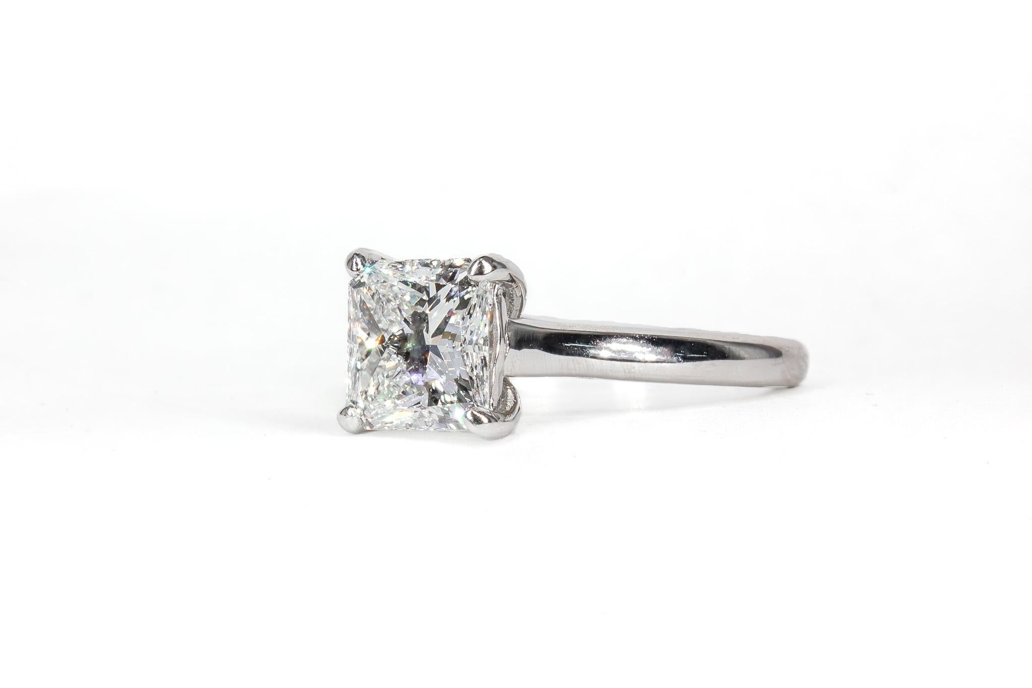 This elegant platinum solitaire ring showcases a timeless design with a refined trellis motif setting, highlighting the beauty of its exceptional center stone. At its heart is a 1.83 carat radiant cut diamond, certified by GIA as G color and VS2