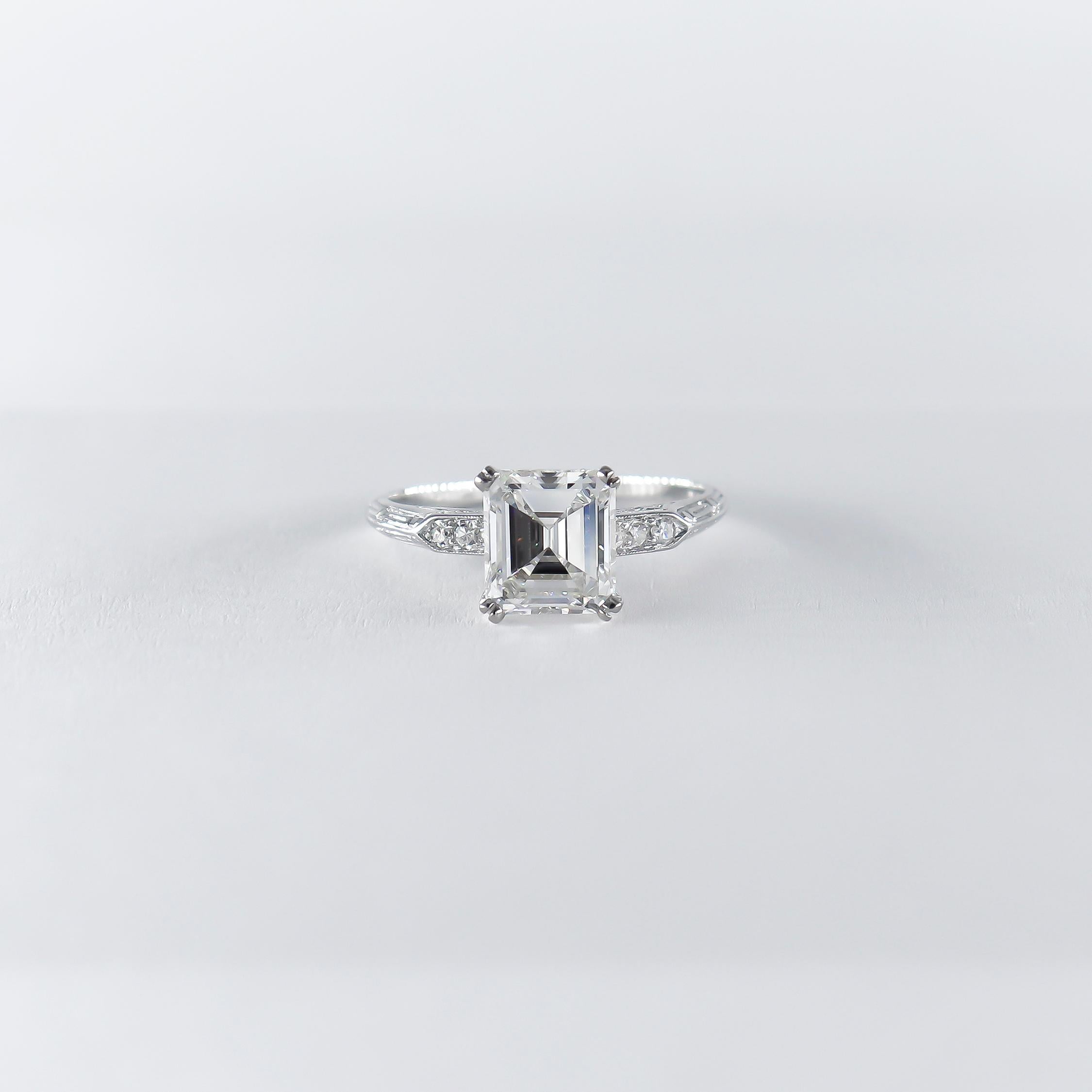 This charming ring from the J. Birnbach vault features a certified 1.73 carat emerald cut diamond of G color and VS2 clarity as described by GIA grading report #6224257297. Set in a handmade, platinum ring with bright-cut pavé and hand engraved