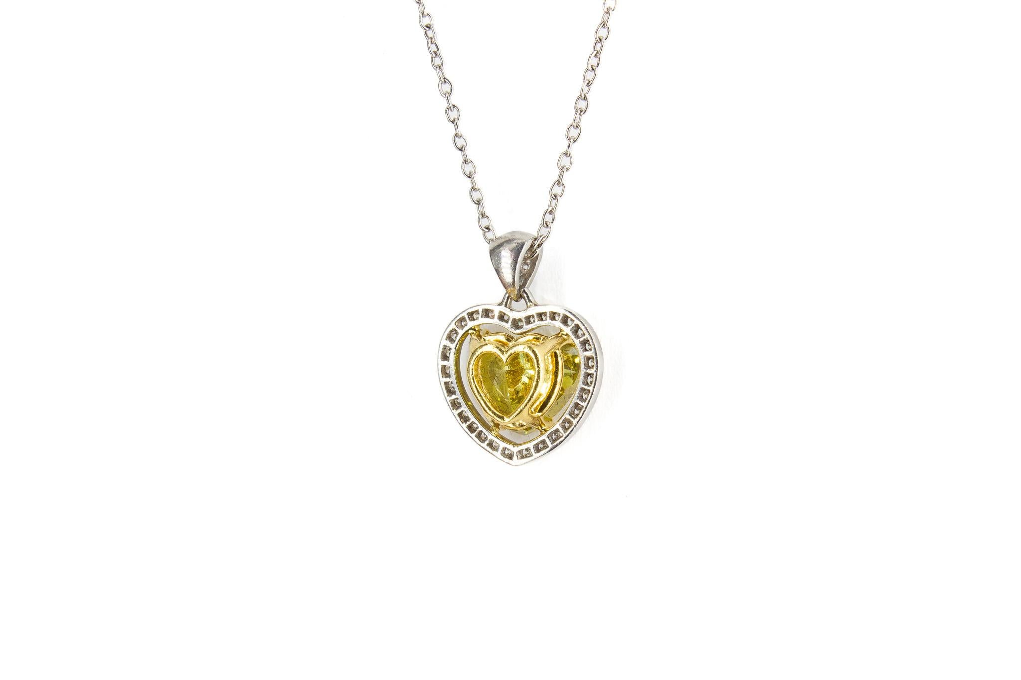 Celebrate love and elegance with this exquisite heart-shaped diamond pendant necklace. At its center lies a 1.82 carat fancy yellow diamond, expertly cut into a heart shape to radiate vibrant warmth and brilliance. This extraordinary gem is