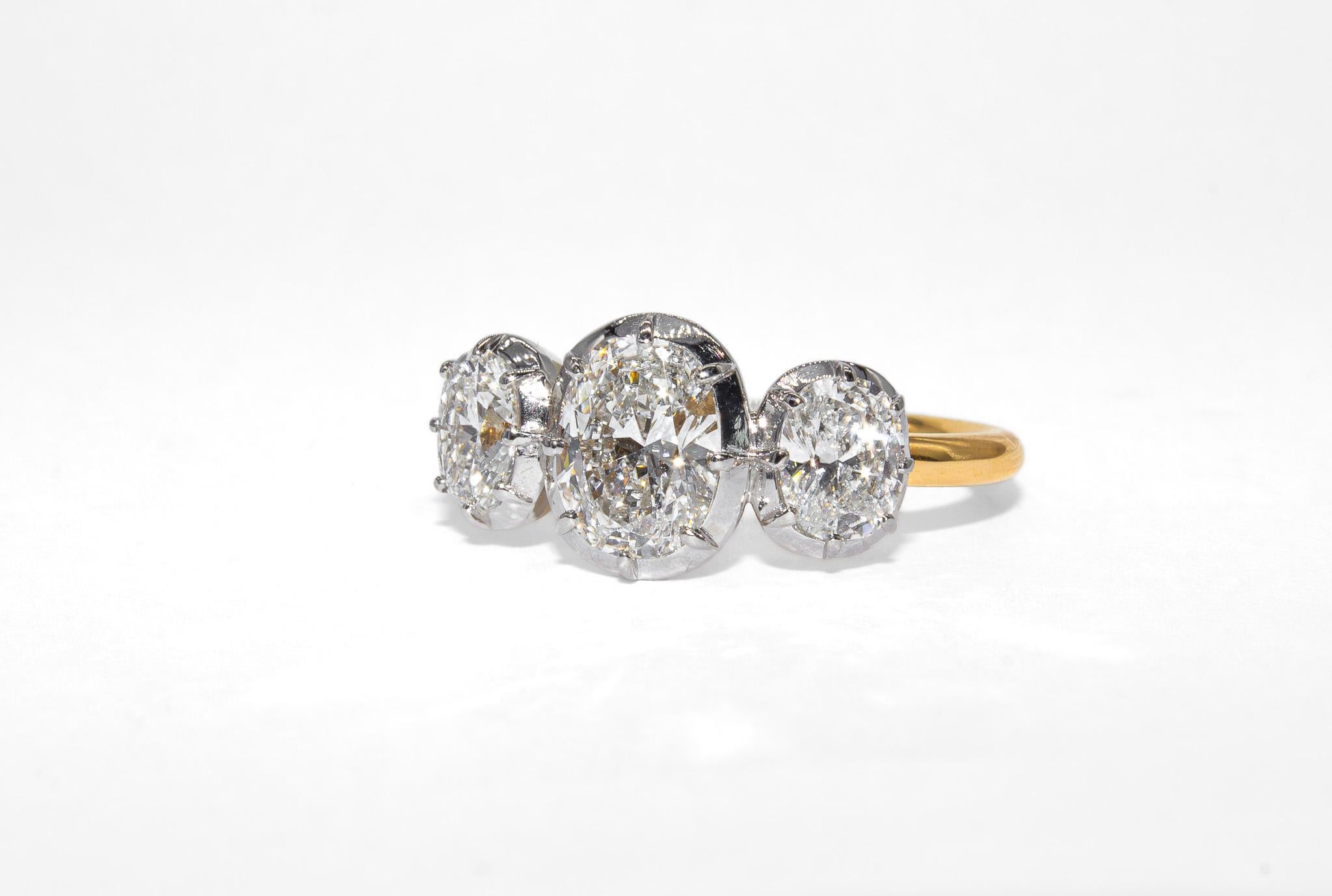 Este refinado anillo de tres piedras de J. Birnbach es una celebración atemporal del equilibrio, el brillo y una artesanía excepcional. En el centro hay un diamante brillante en cojín de 0,98 quilates, con certificado GIA de color E y claridad VS1,