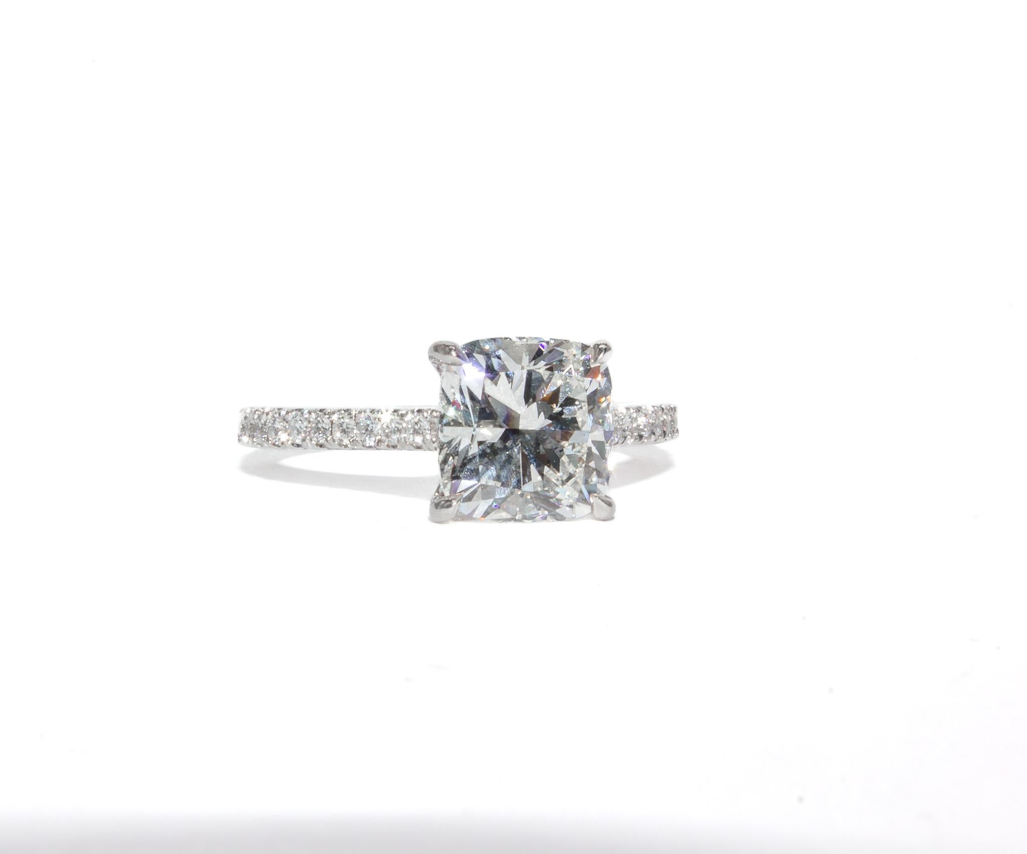 This elegant platinum pavé ring showcases a timeless design with a dazzling center diamond and intricate detailing. At its heart is a 2.01 carat cushion cut diamond, graded I color and VS1 clarity by GIA, offering exceptional brilliance and a