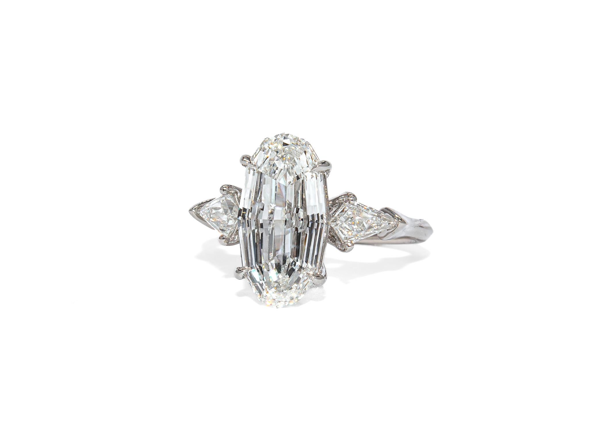 This distinctive three-stone ring by J. Birnbach showcases the sophisticated geometry of a 3.01 carat step-cut oval diamond, certified by GIA as G color and SI2 clarity. A rare and architectural take on the classic oval shape, the step-cut faceting