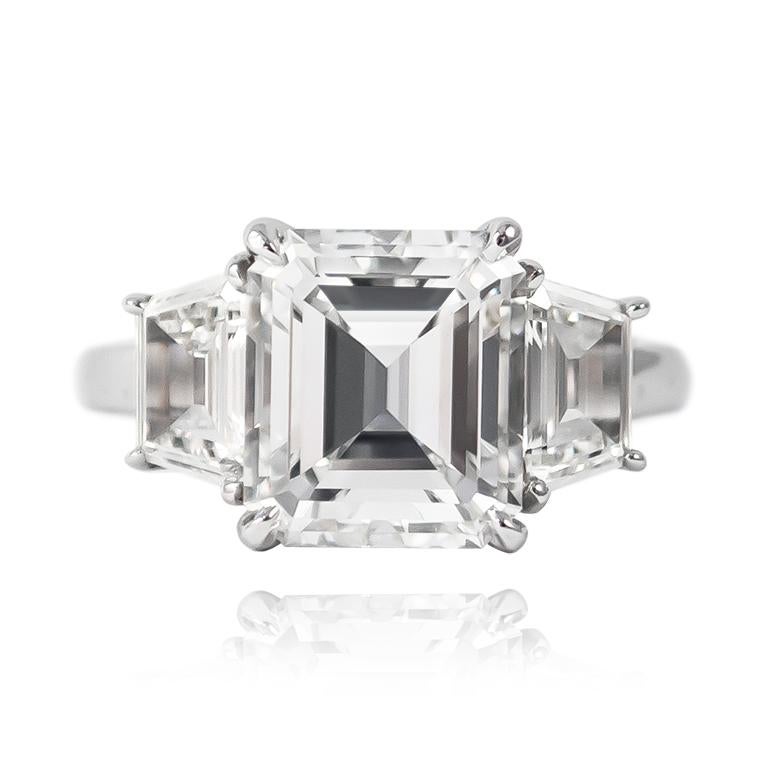 This mesmerizing ring features a 3.04 ct Emerald cut of E color and VS1 clarity. Set in a handmade, platinum setting with step-cut trapezoid side stones = 1.12 ctw, this piece is a breathtaking look that is guaranteed to make them stop and stare!