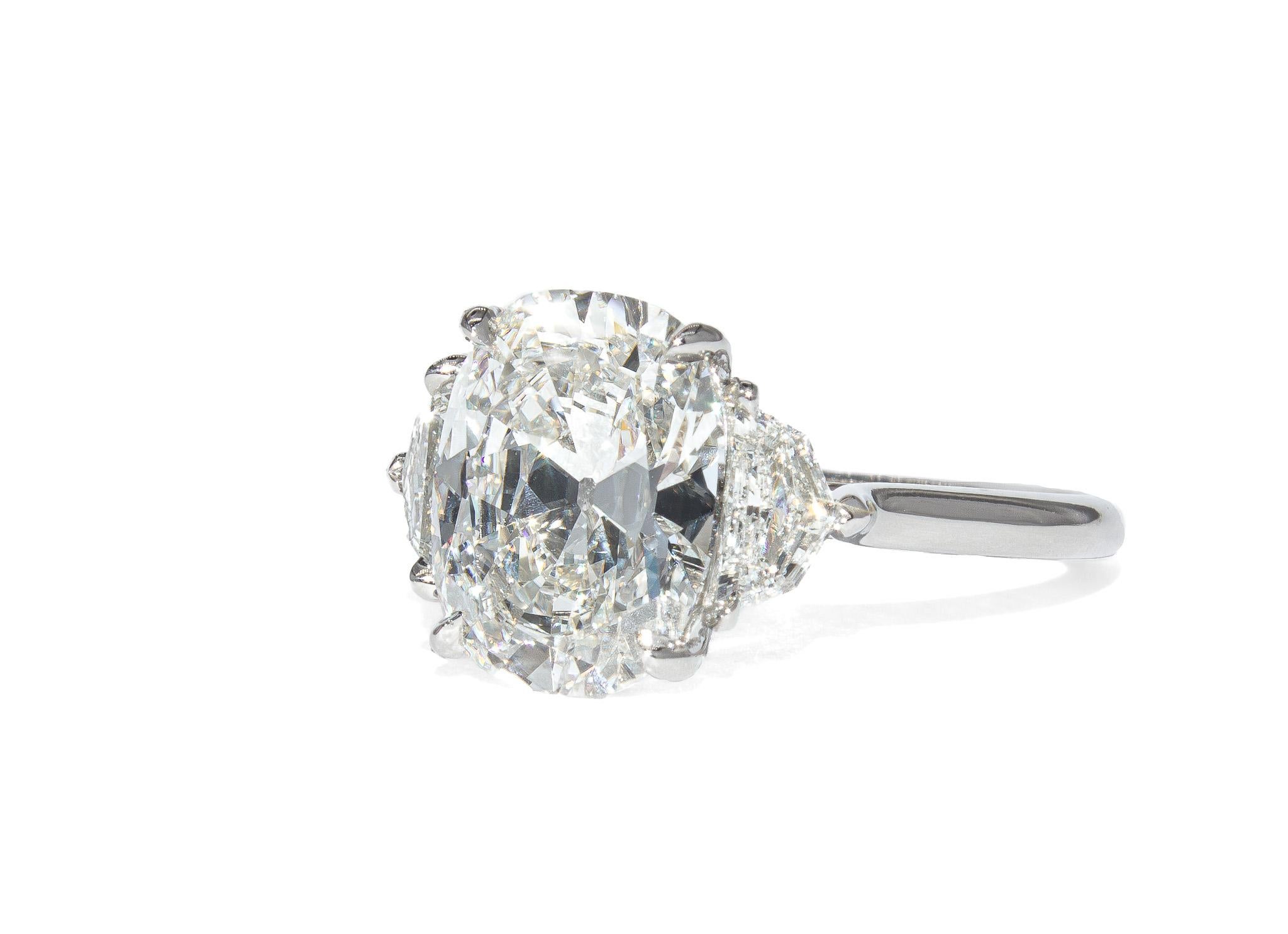 This refined three-stone ring from J. Birnbach pairs timeless elegance with bold proportions. At the heart of the design is a 3.14 carat antique elongated cushion brilliant diamond, certified by GIA as a D color and VS1 clarity. The center stone