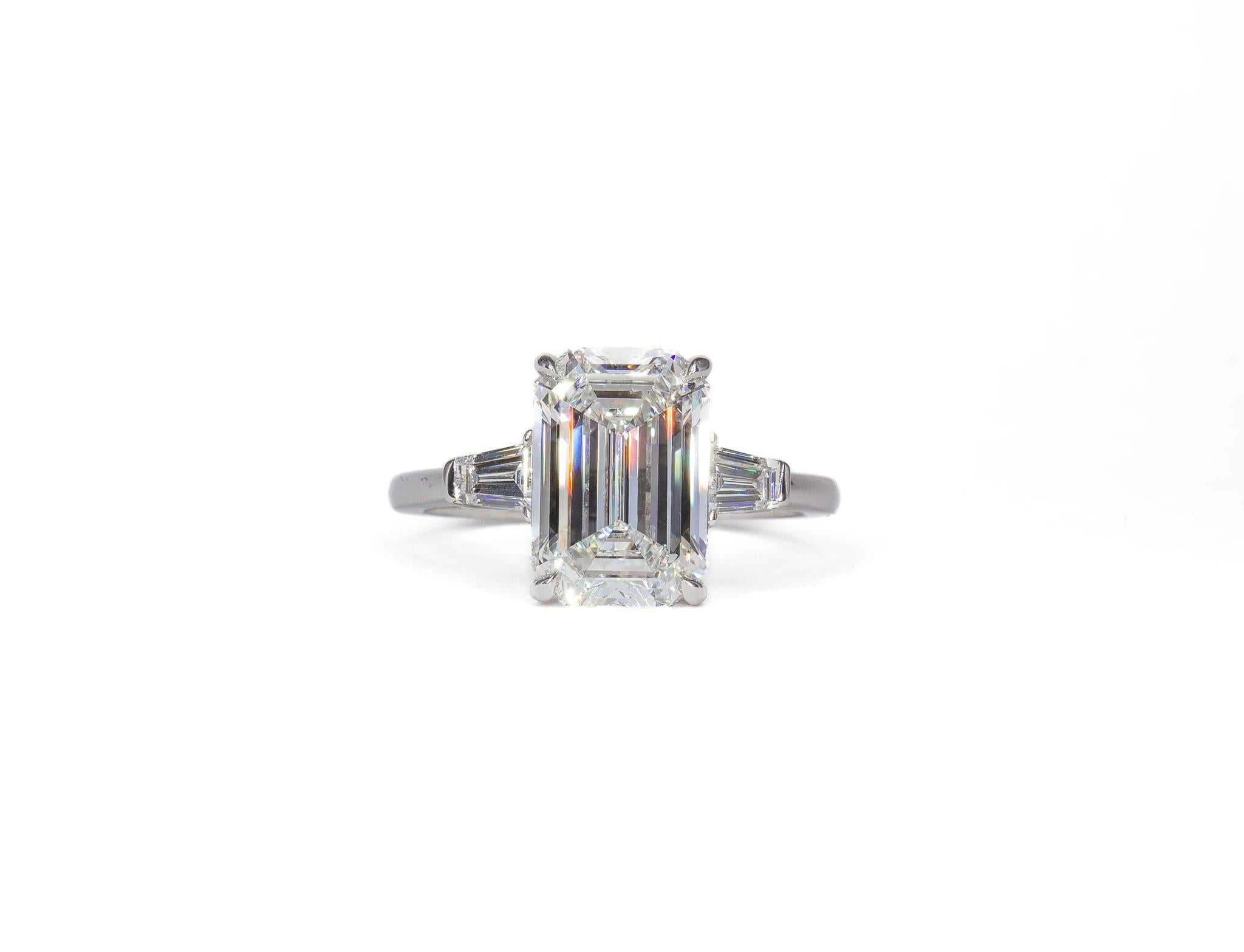 This elegant platinum three-stone ring showcases a magnificent 3.03 carat emerald cut diamond, GIA certified F color and VS2 clarity. The center stone’s exceptional clarity and color are perfectly complemented by two tapered baguette side stones,