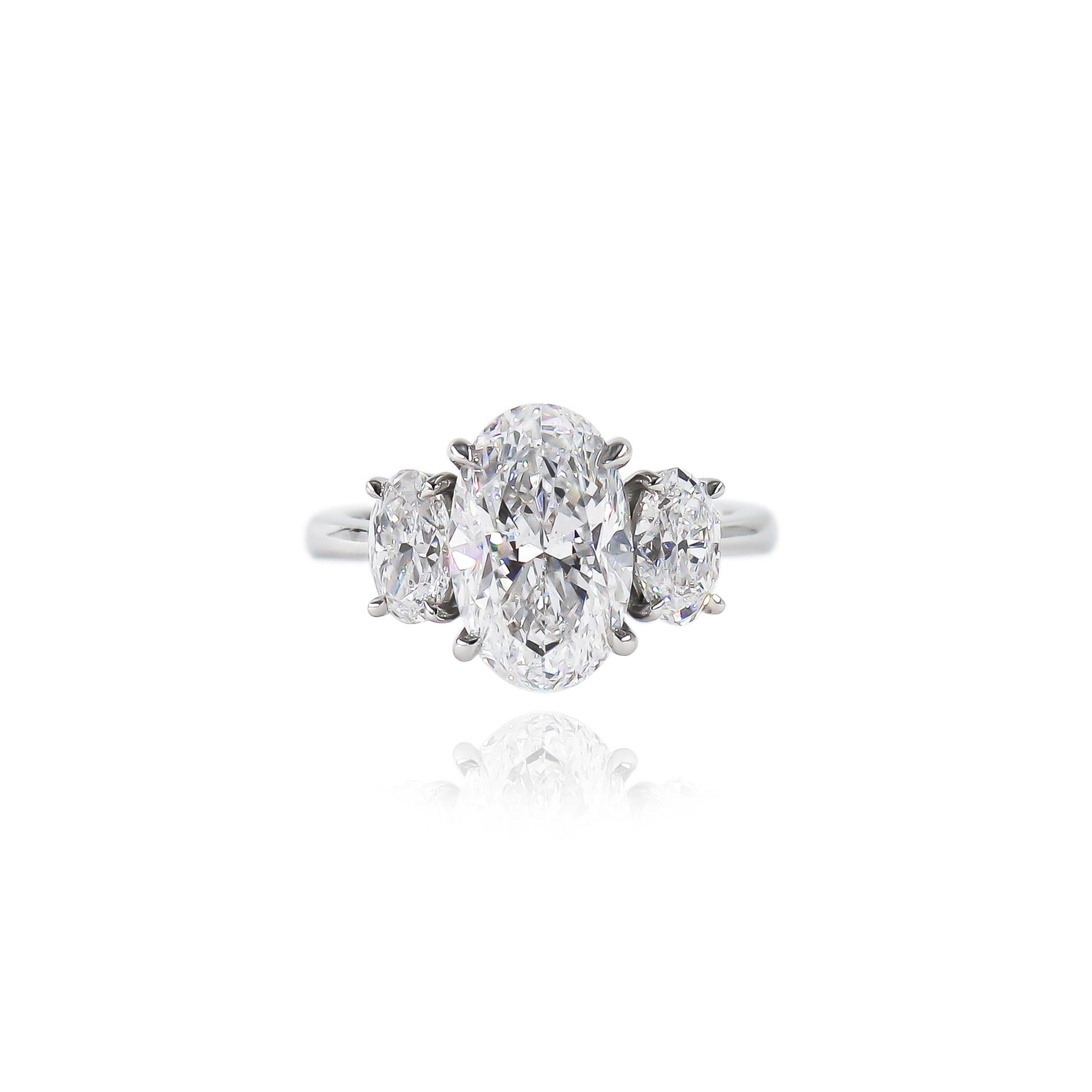 This glamorous three stone ring is the perfect statement piece! The unique combination of three oval shaped diamonds fully covers the finger for maximum sparkle. The 3.18 carat center diamond is a GIA certified D color and SI1 clarity. Its elongated